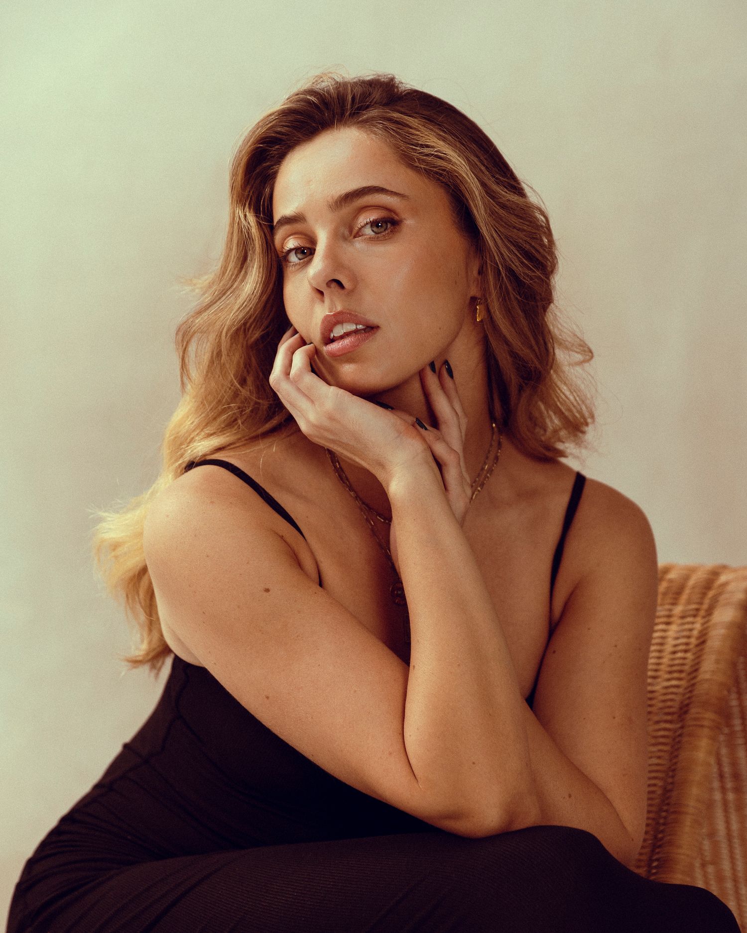 Warm-toned fashion portraits showing intimate poses on wicker chair.