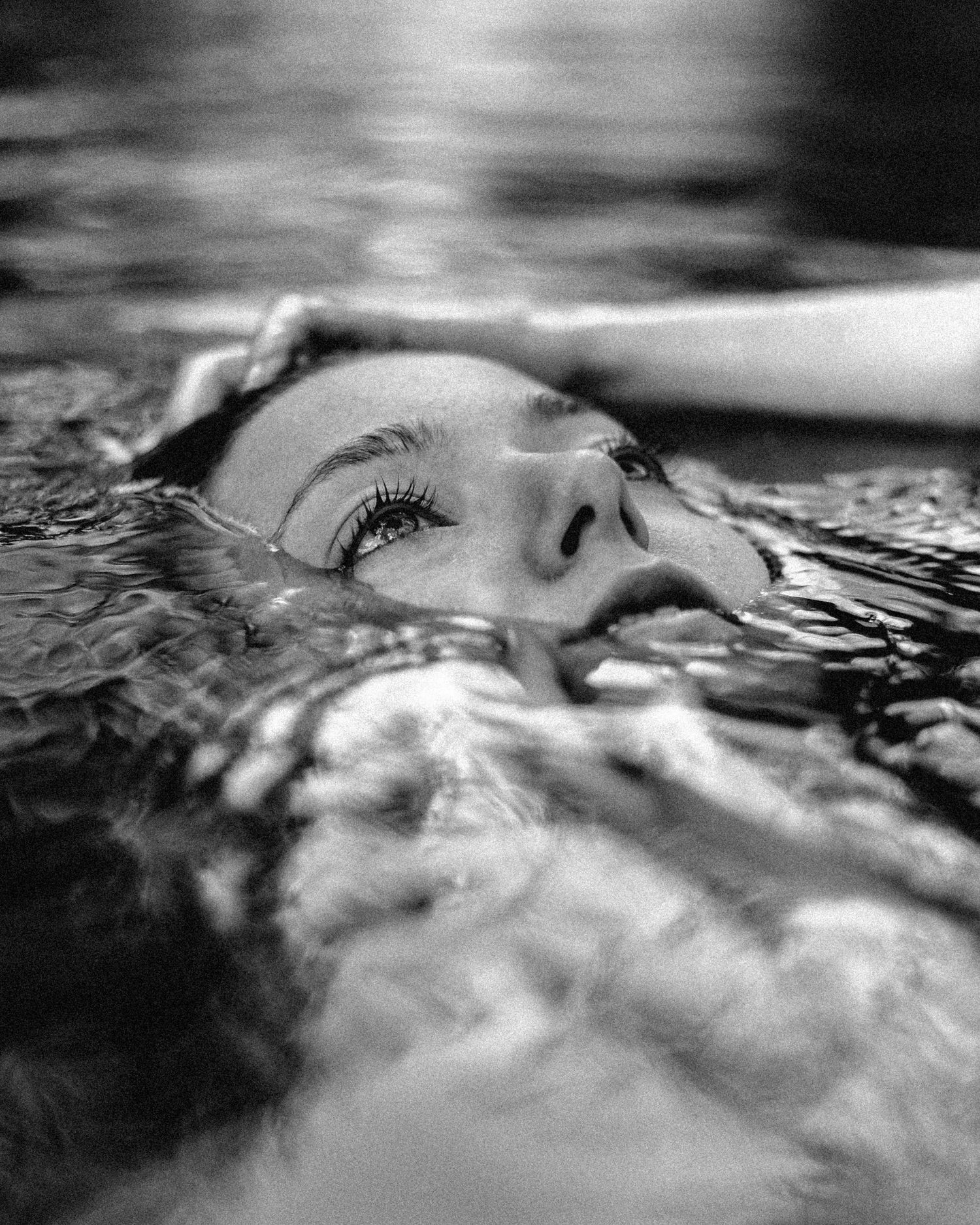 Black and white artistic portrait of someone floating in water.