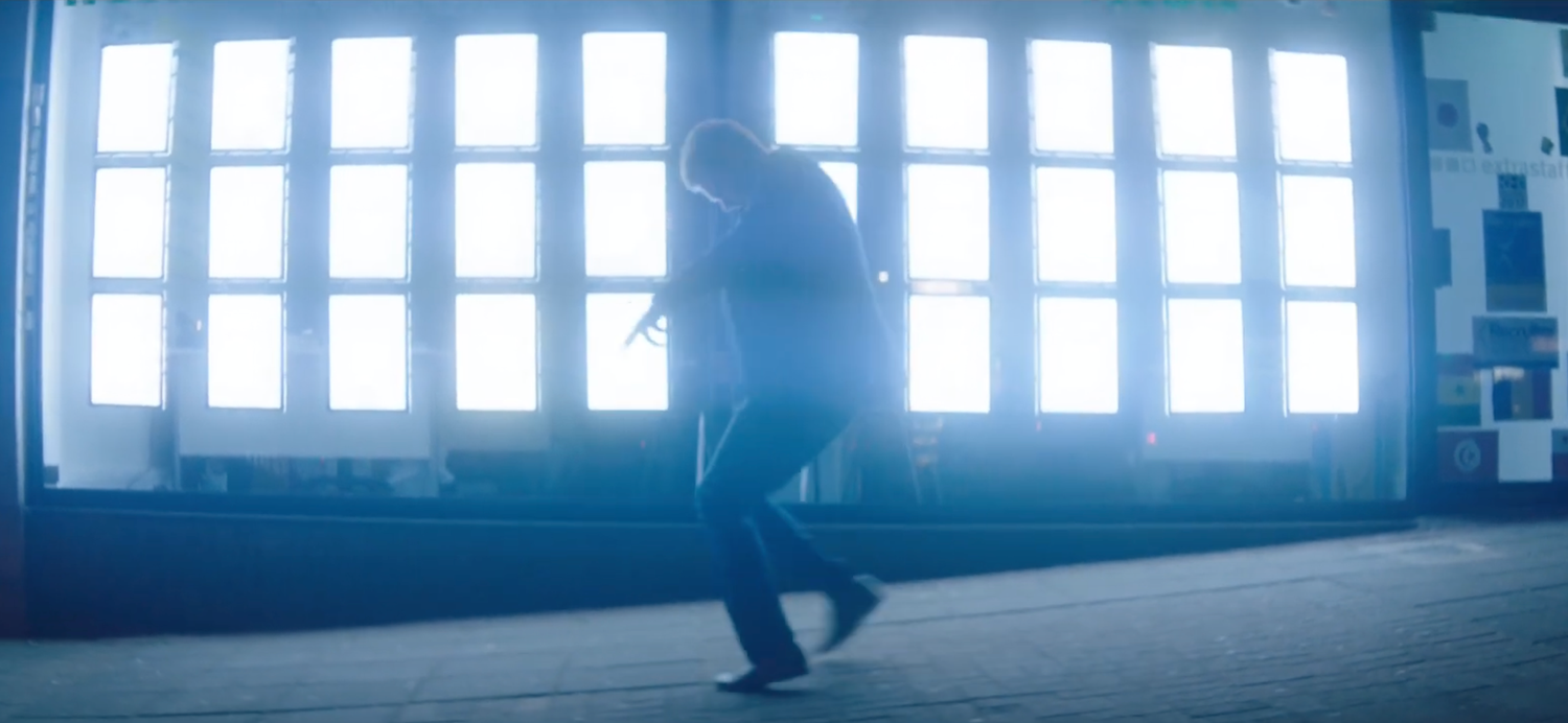 Person dancing in silhouette against bright windowpane background.