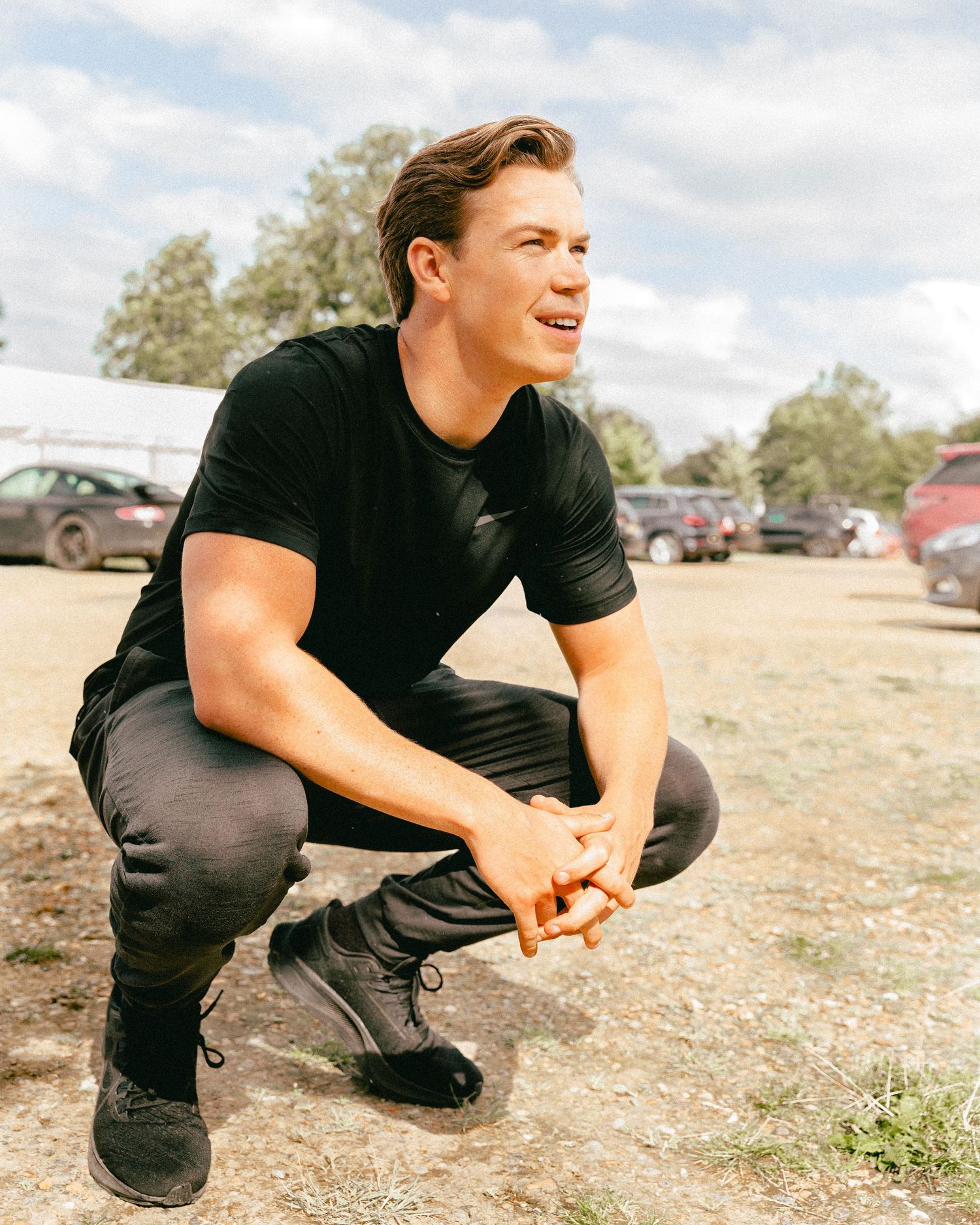 Someone in dark clothing crouches low to the ground in an outdoor setting.