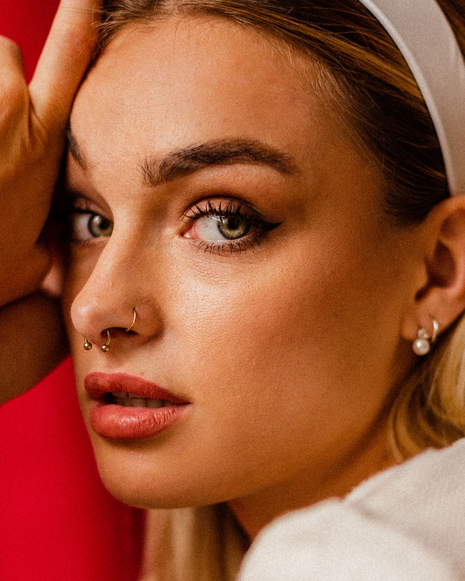 Dramatic beauty portraits against red backdrop showcasing glamorous makeup and jewelry.