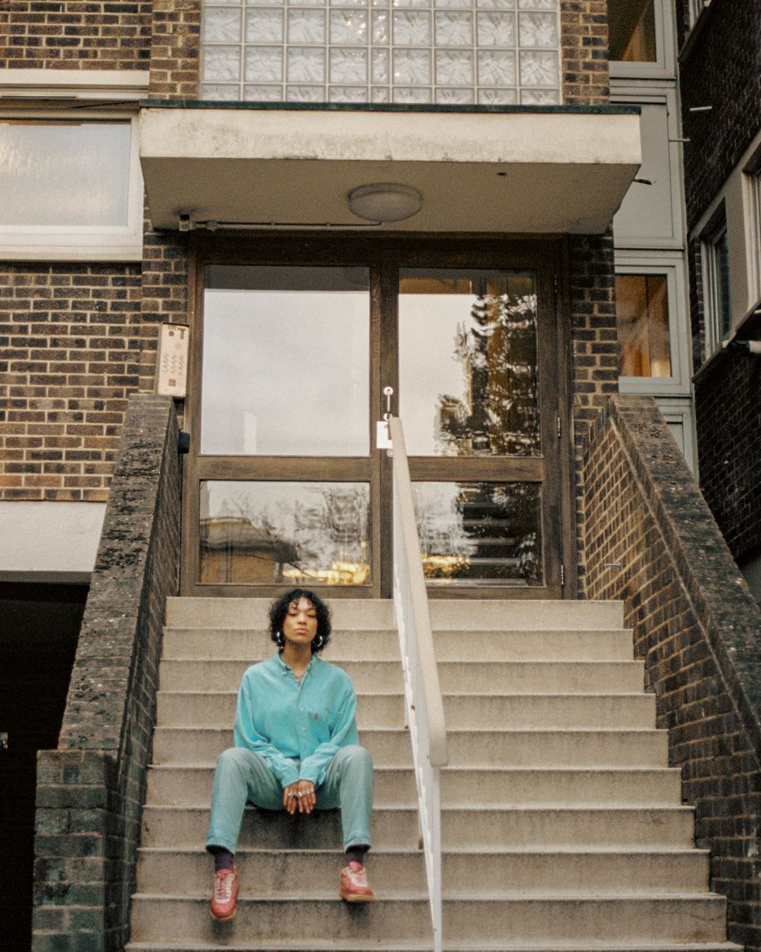 Casual portrait sitting on concrete steps wearing mint shirt and light denim.