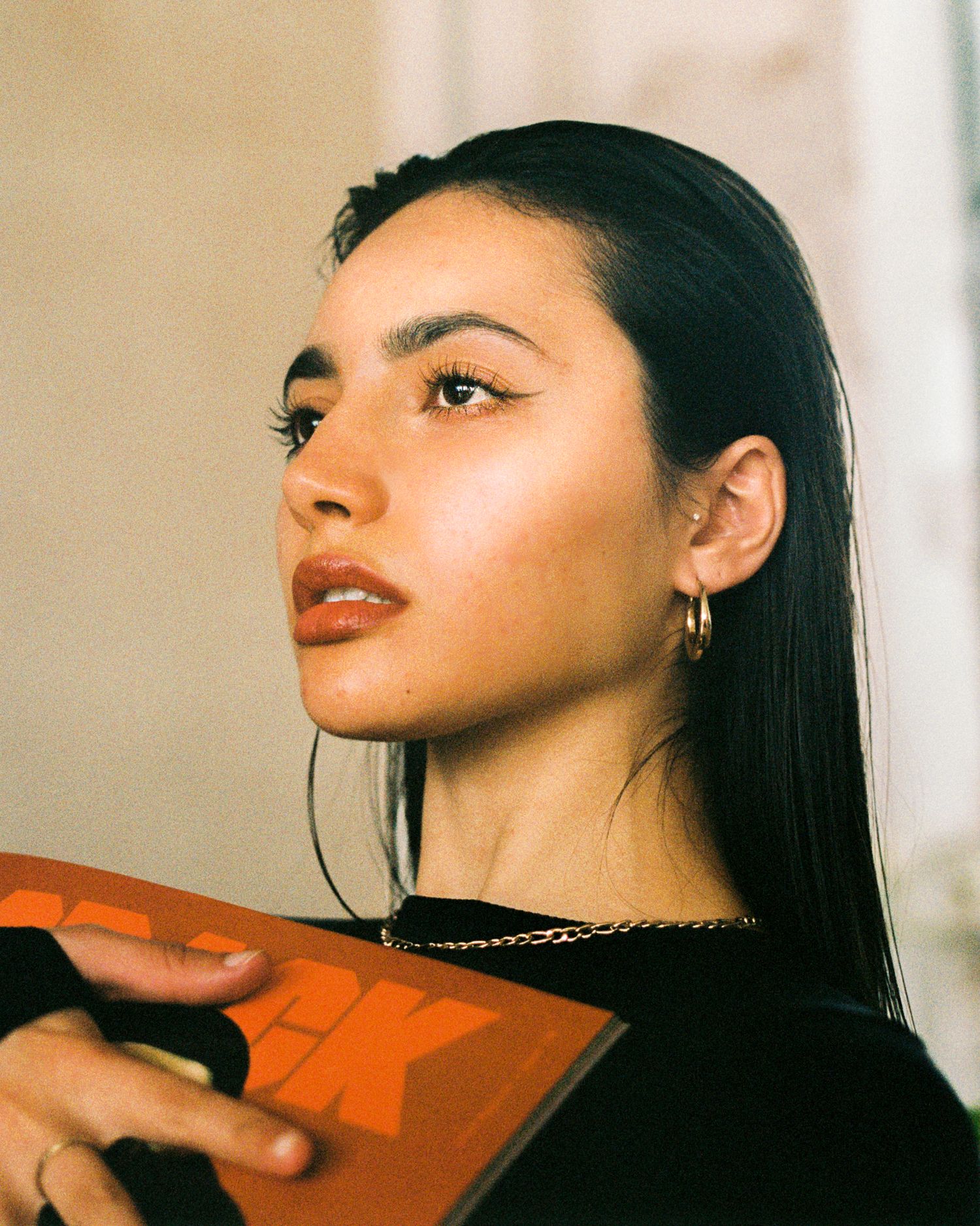 Artistic profile portrait featuring dark hair and a gold chain necklace.