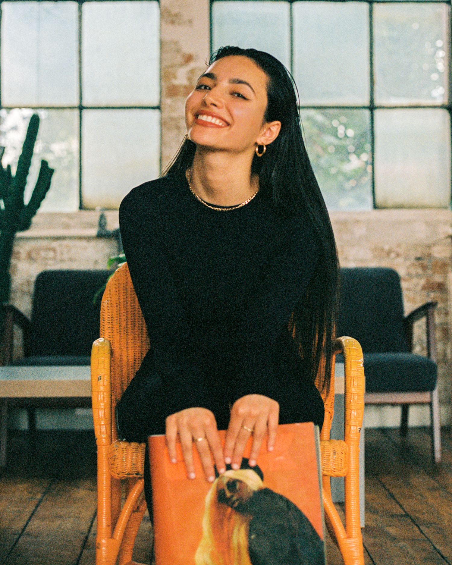 Candid seated portrait with an orange book on a wooden chair.