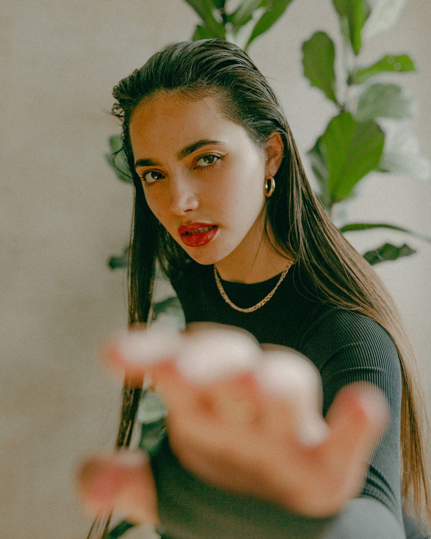 Fashion portrait with tropical plants featuring black top and gold necklace.