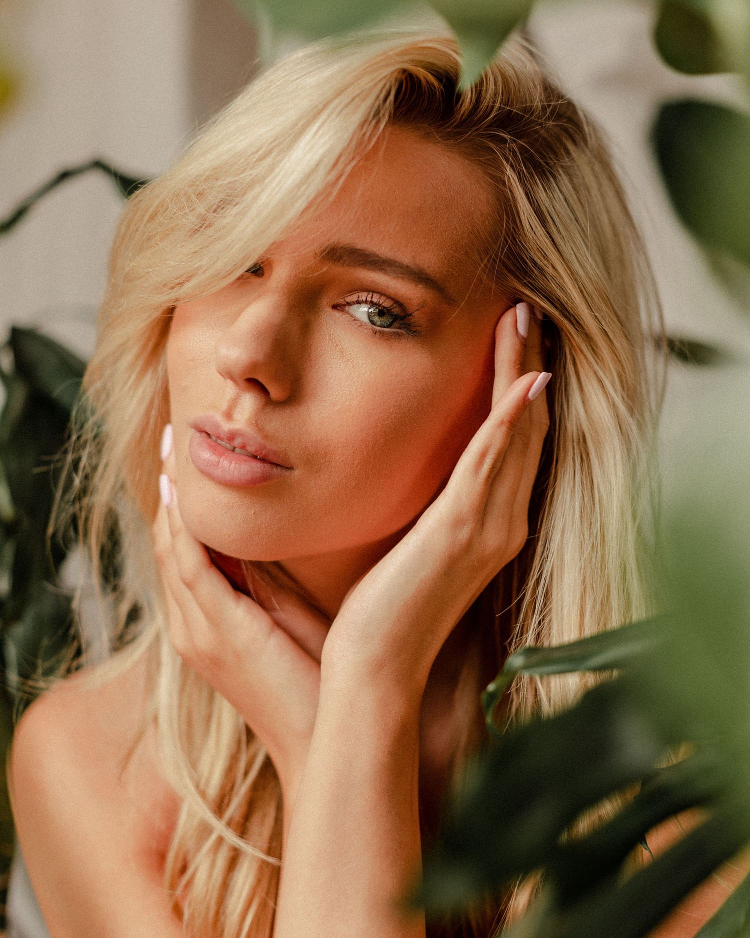 Artistic beauty shot among tropical leaves with warm lighting and soft focus.
