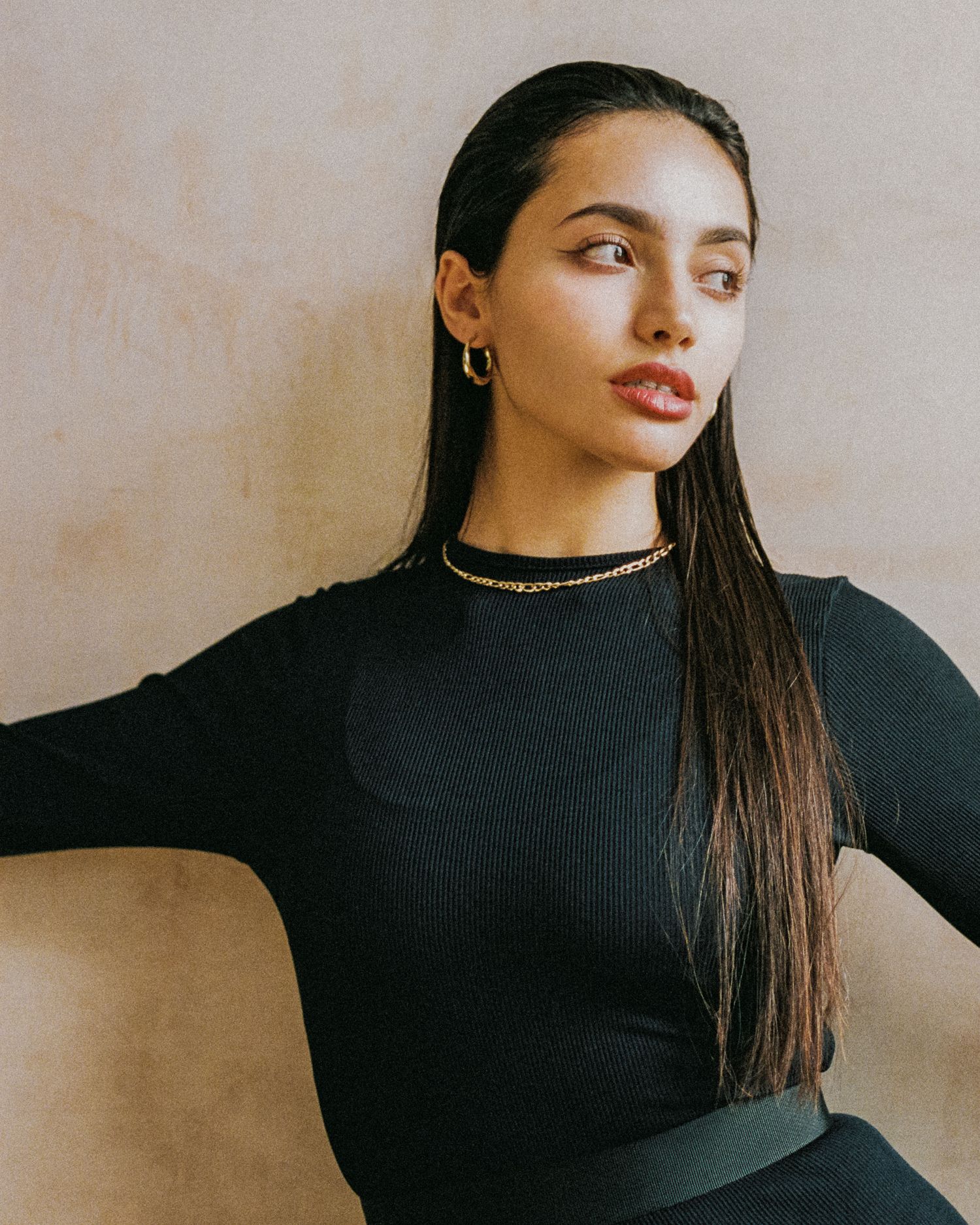 Elegant studio portrait in a black top with gold accessories.
