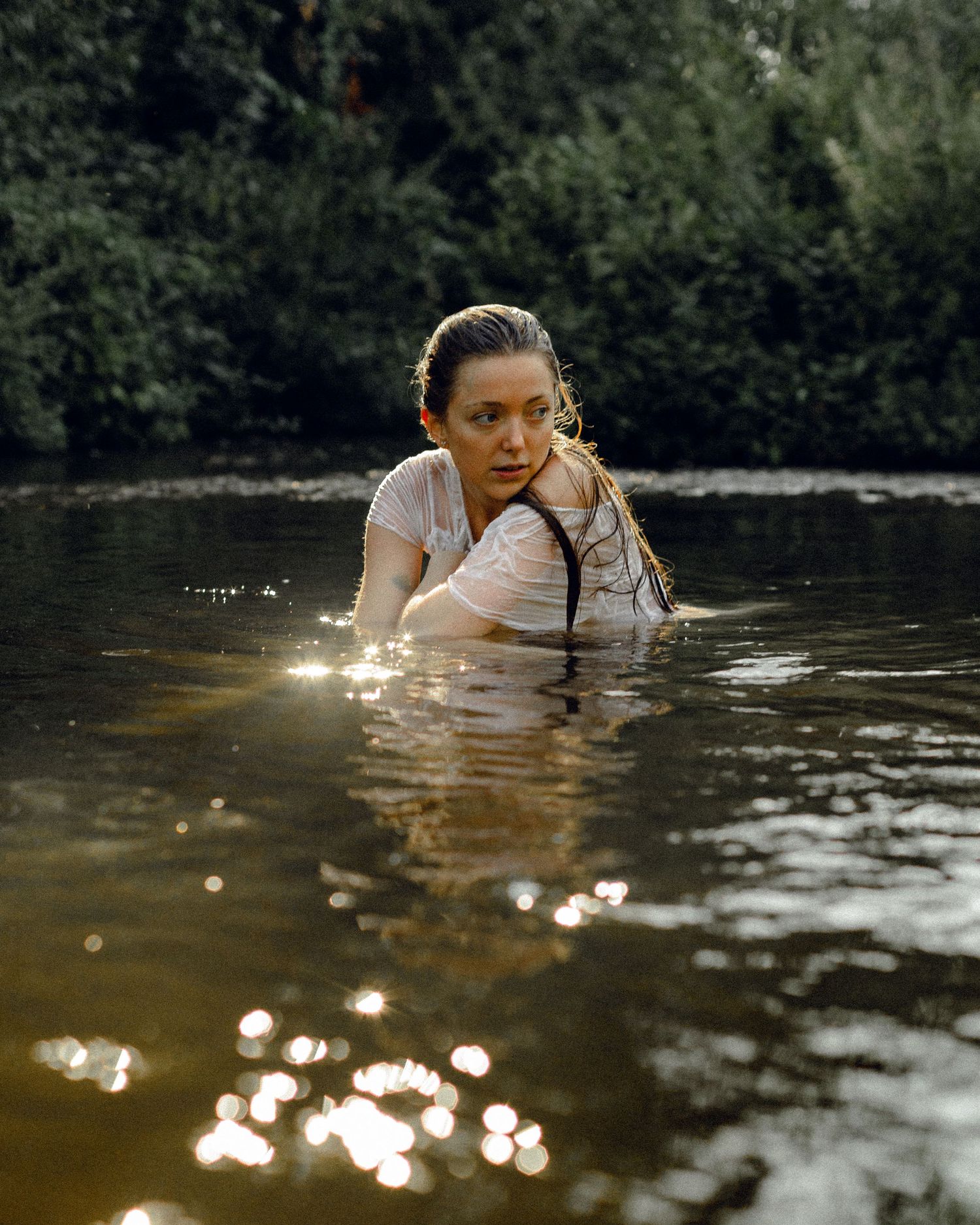Golden sunlit reflections dance on dark water surface during outdoor photo session.