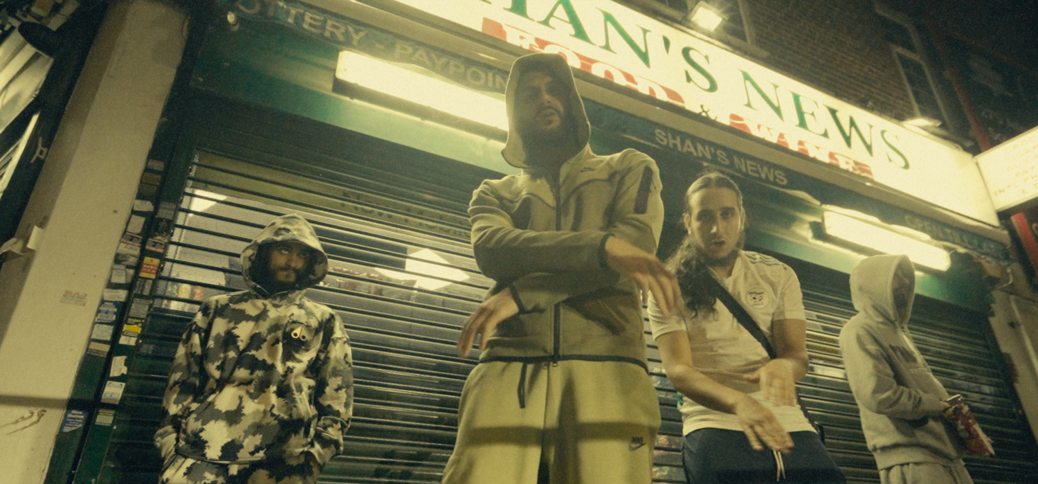 Group of people standing outside a closed storefront at night.