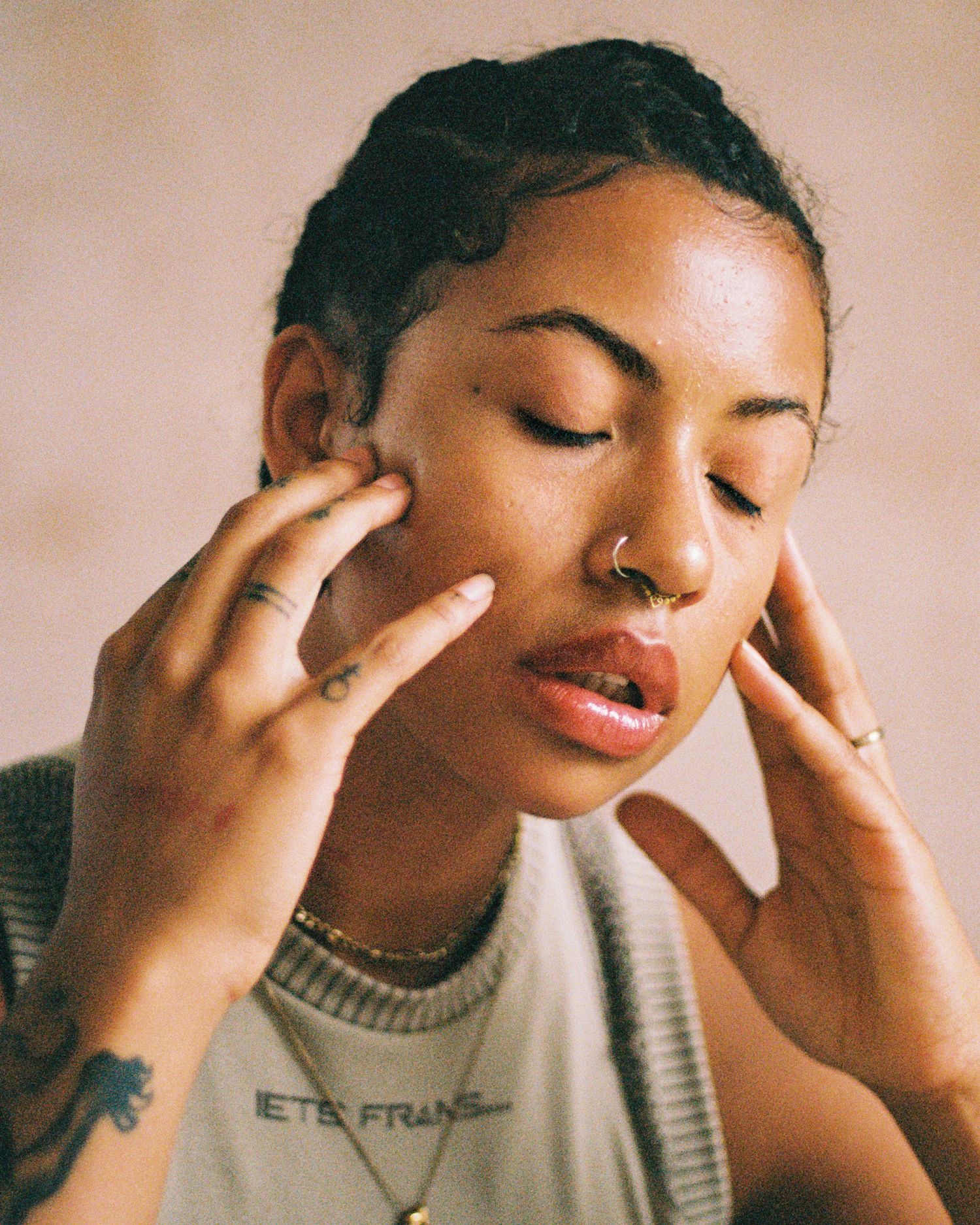 Gentle self-care portrait with closed eyes and hands touching face.