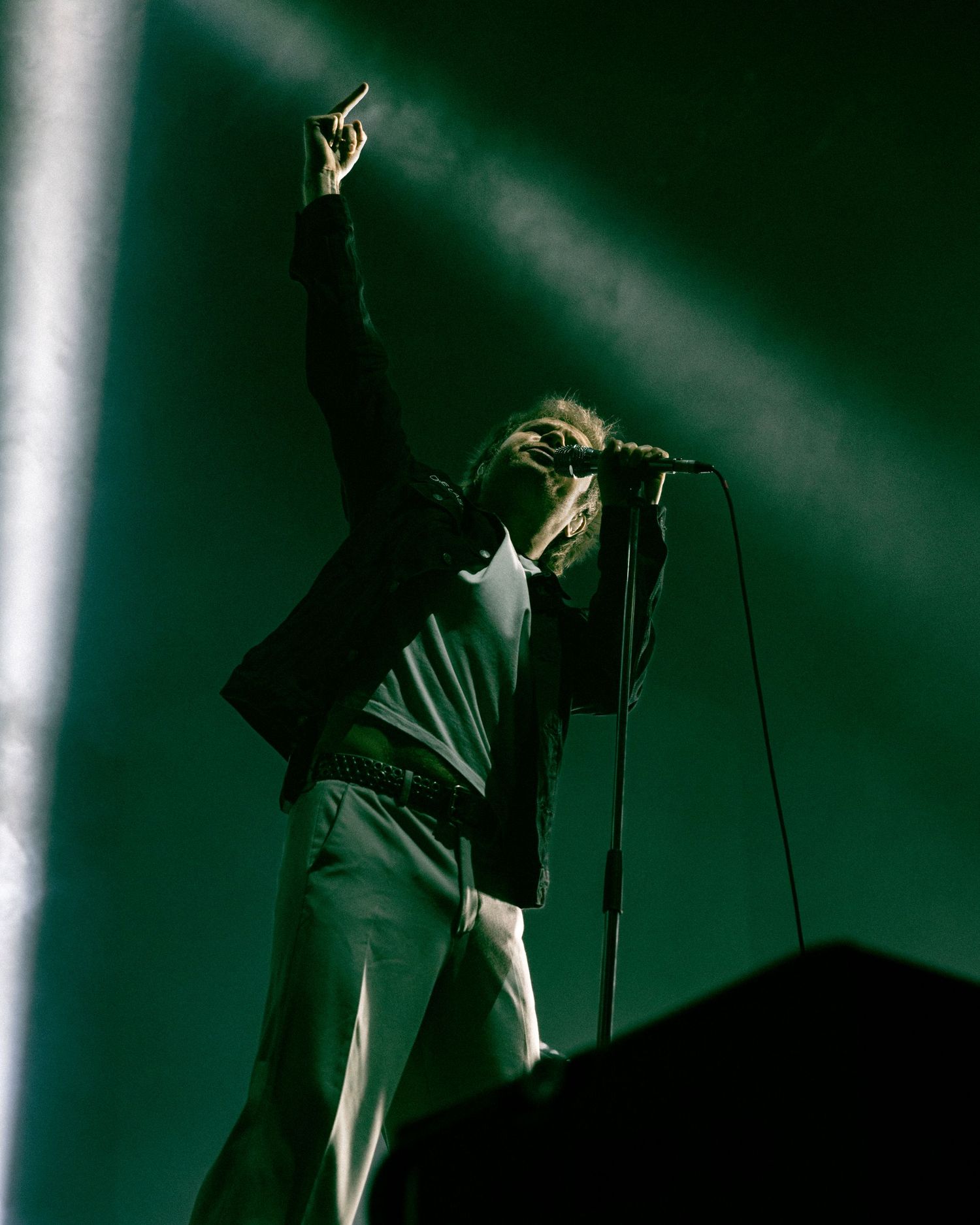 Silhouetted figure performs on stage with dramatic lighting and fog effects in a dark performance venue.