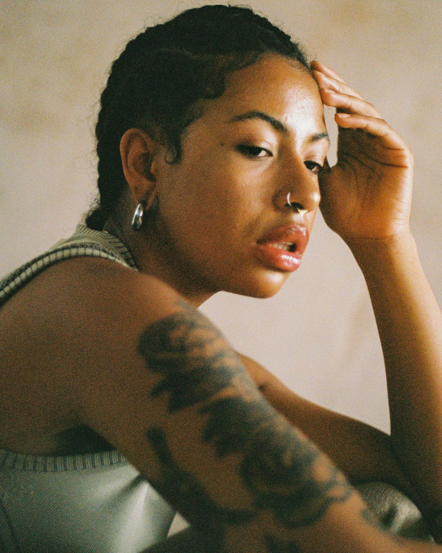 Portrait in warm lighting showing detailed tattoo sleeve and contemplative pose.