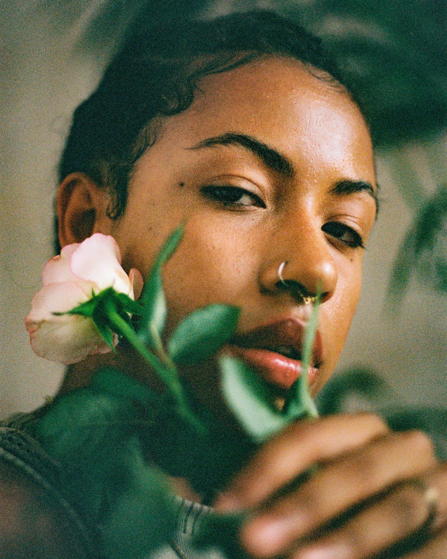 Artistic portrait with pink rose and foliage in moody lighting.