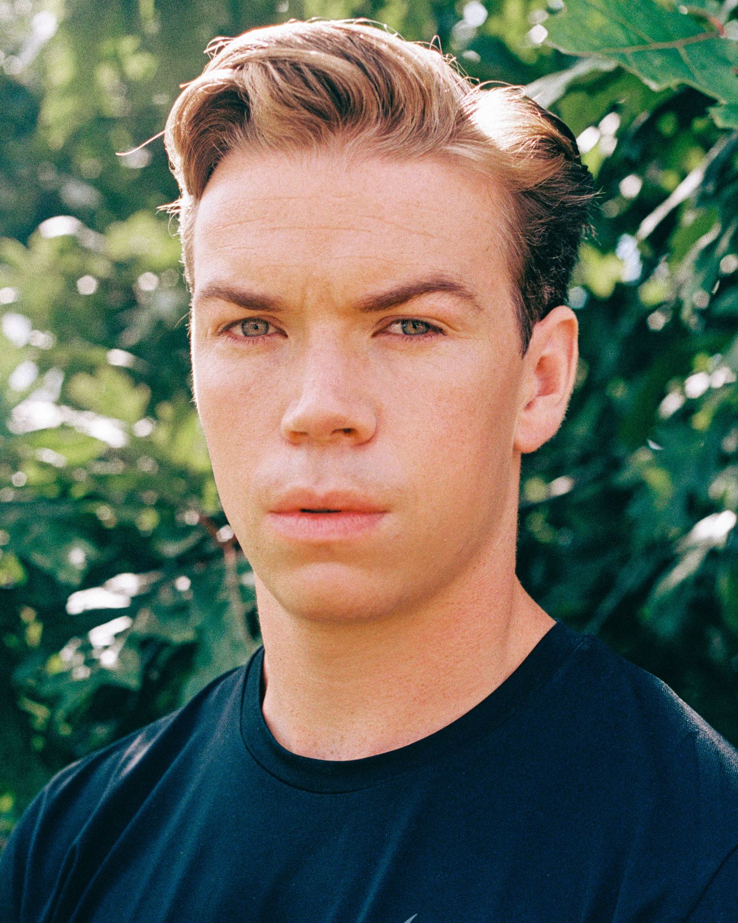 Close-up outdoor portrait with natural lighting and green foliage background.