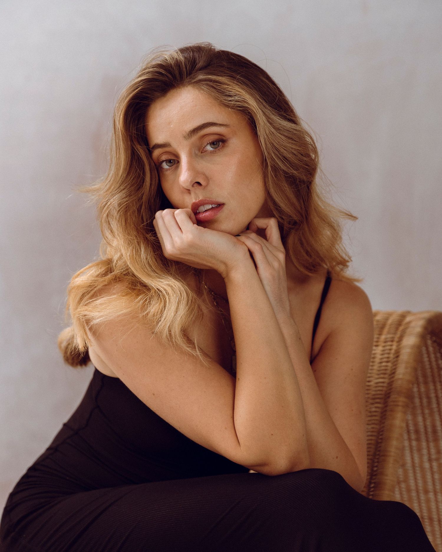 Glamour portrait with wavy blonde hair against neutral backdrop.