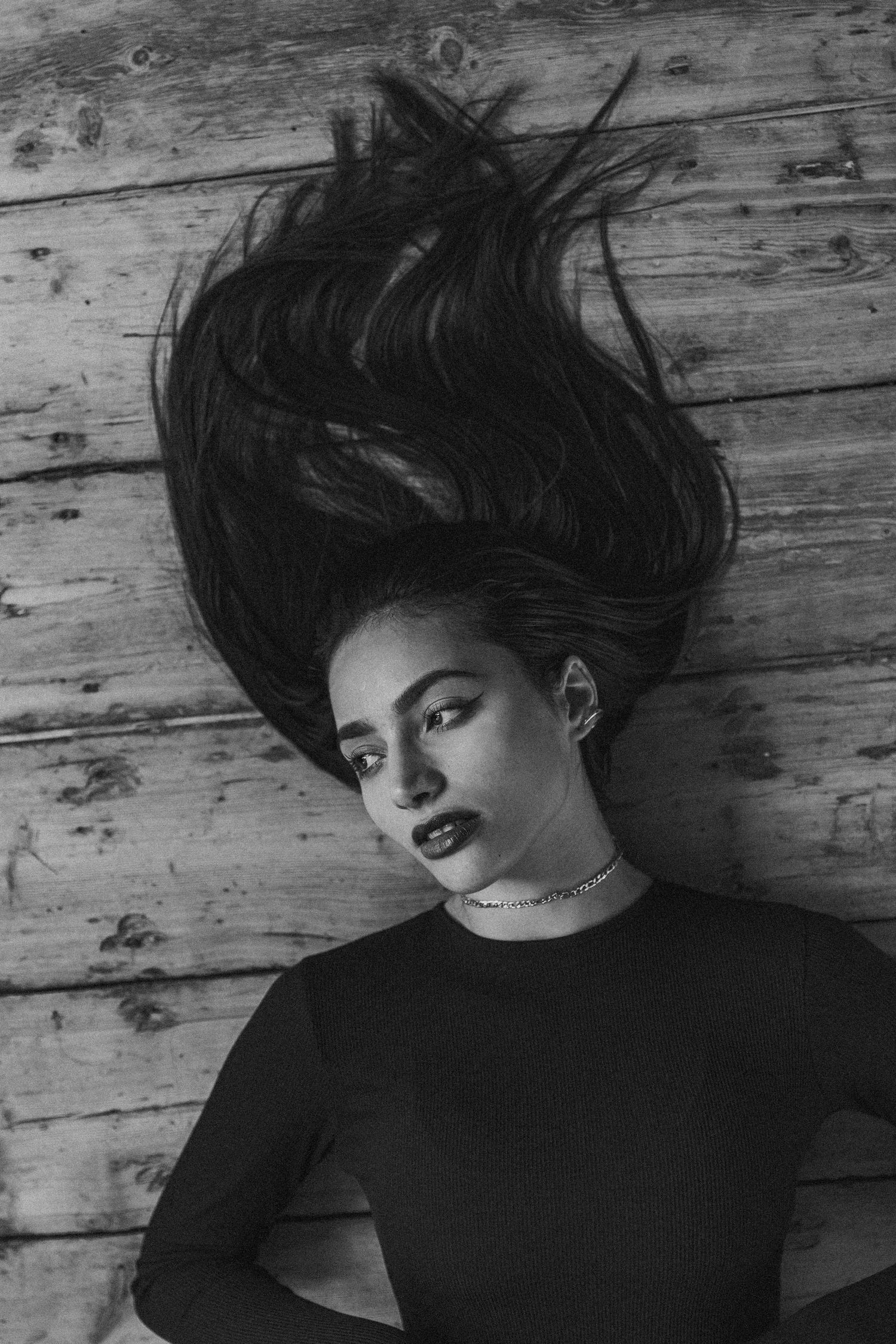 Artistic black and white photo with hair fanned out against rustic wooden background.