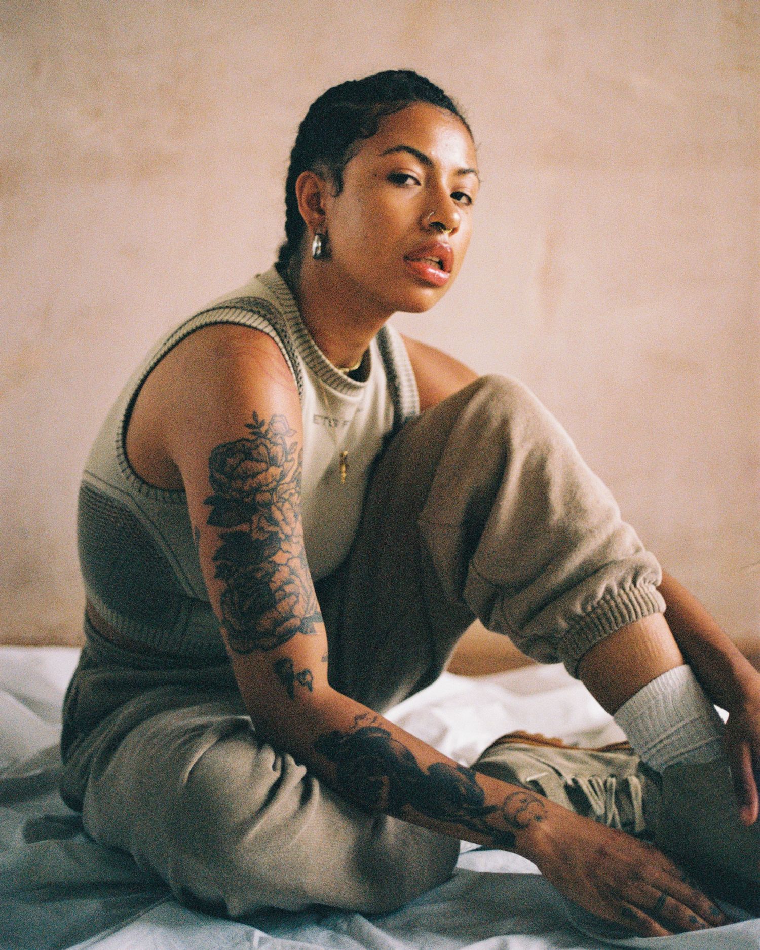 Relaxed casual portrait on bed wearing loungewear and displaying arm tattoos.