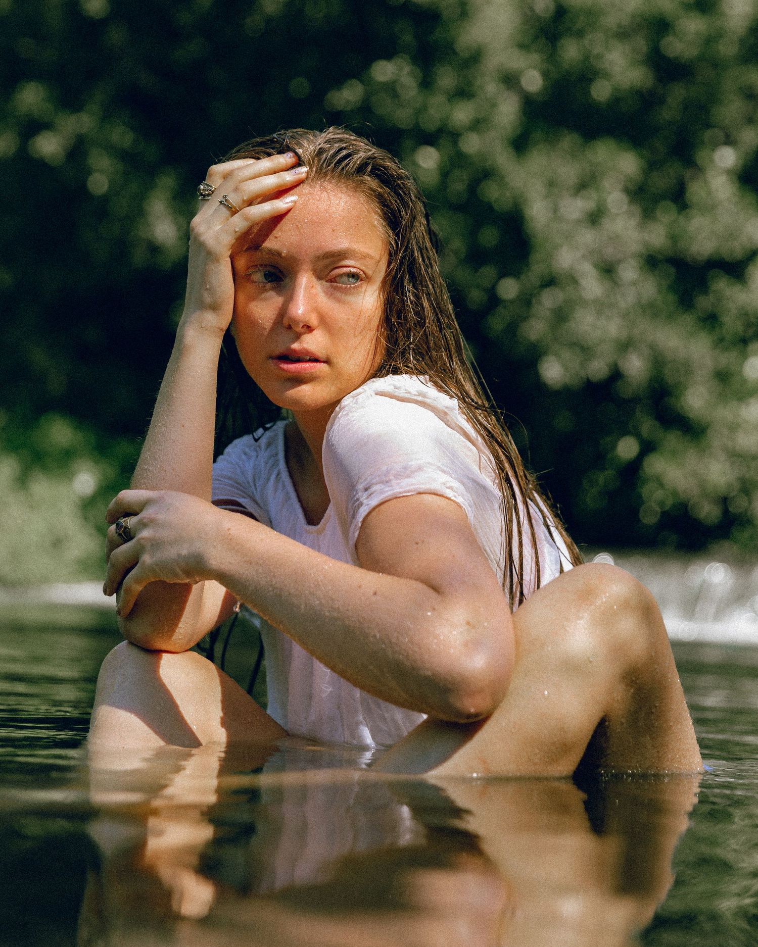 Dreamy water portrait series showing artistic poses with wet clothing in natural outdoor lighting.