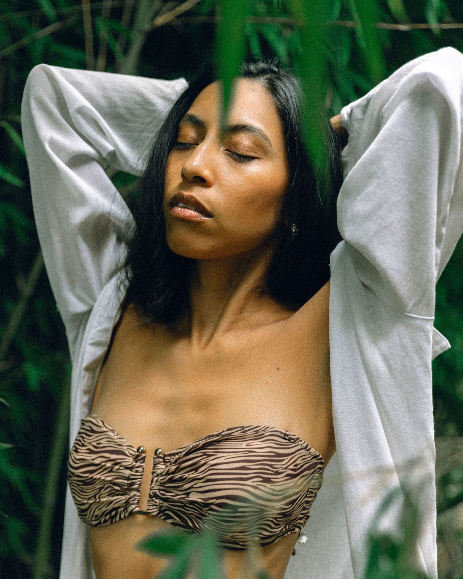 Fashion portrait with white jacket against tropical bamboo backdrop.