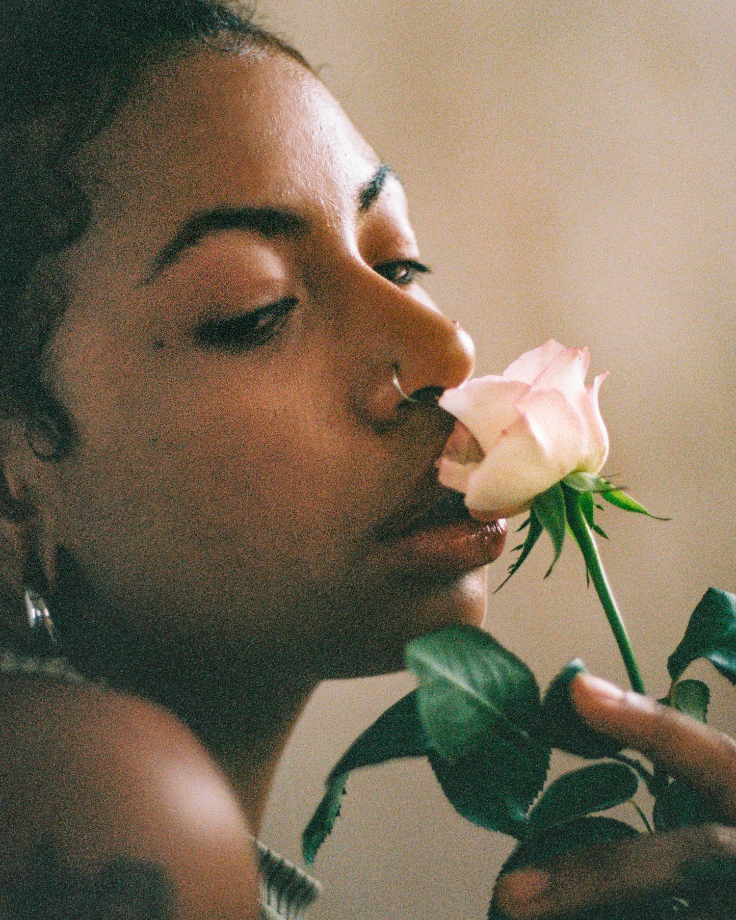Sensual portrait with a pink rose against soft, warm lighting.