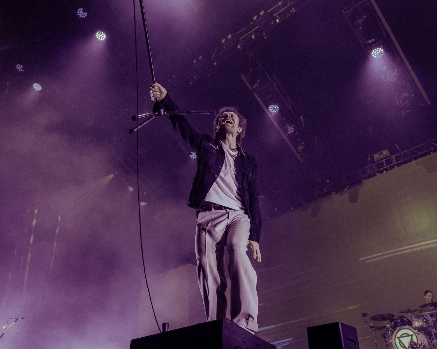 Concert performer silhouetted against purple stage lights during an energetic live performance.