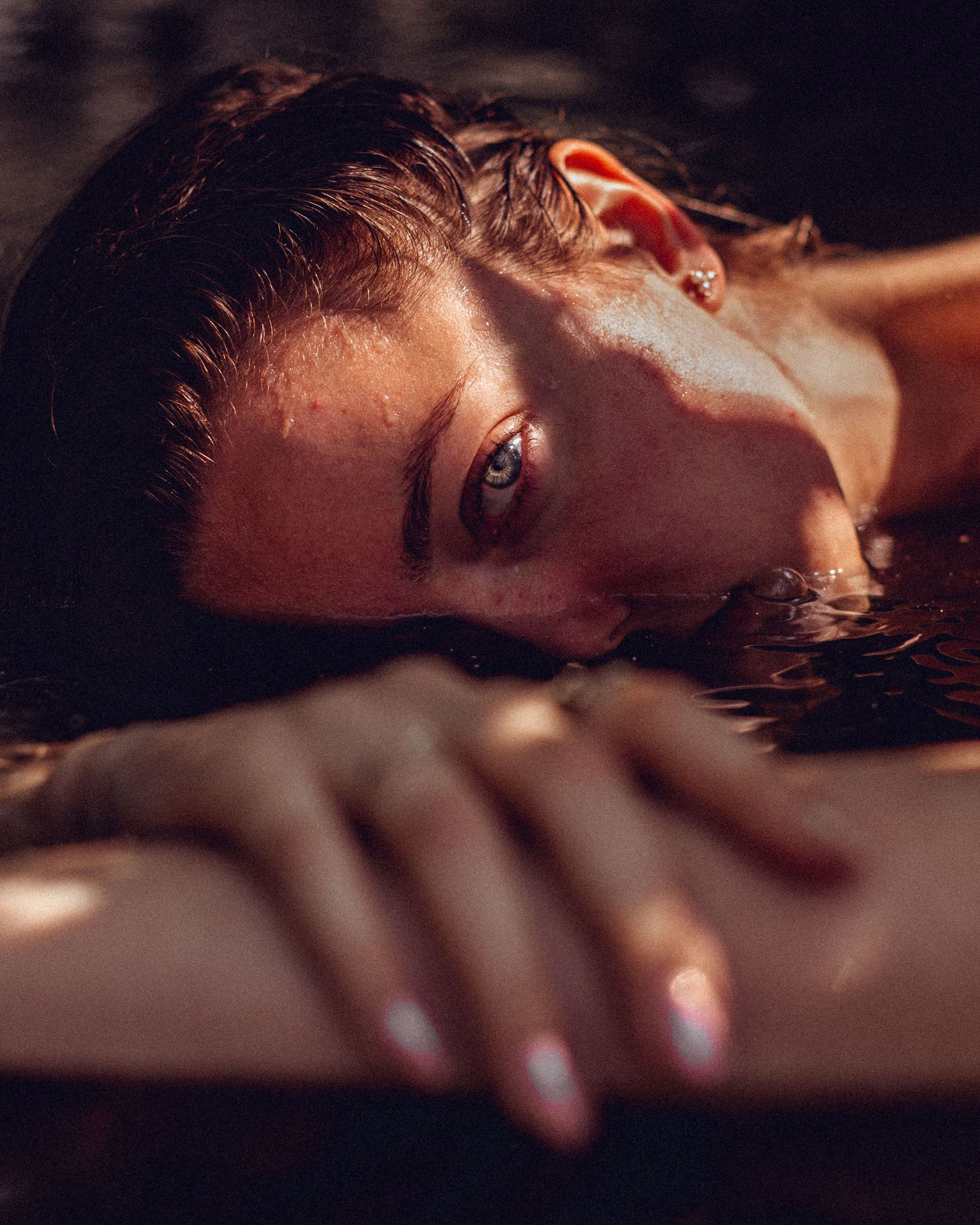 Moody close-up portraits in dark lighting with dramatic shadows and water reflections.