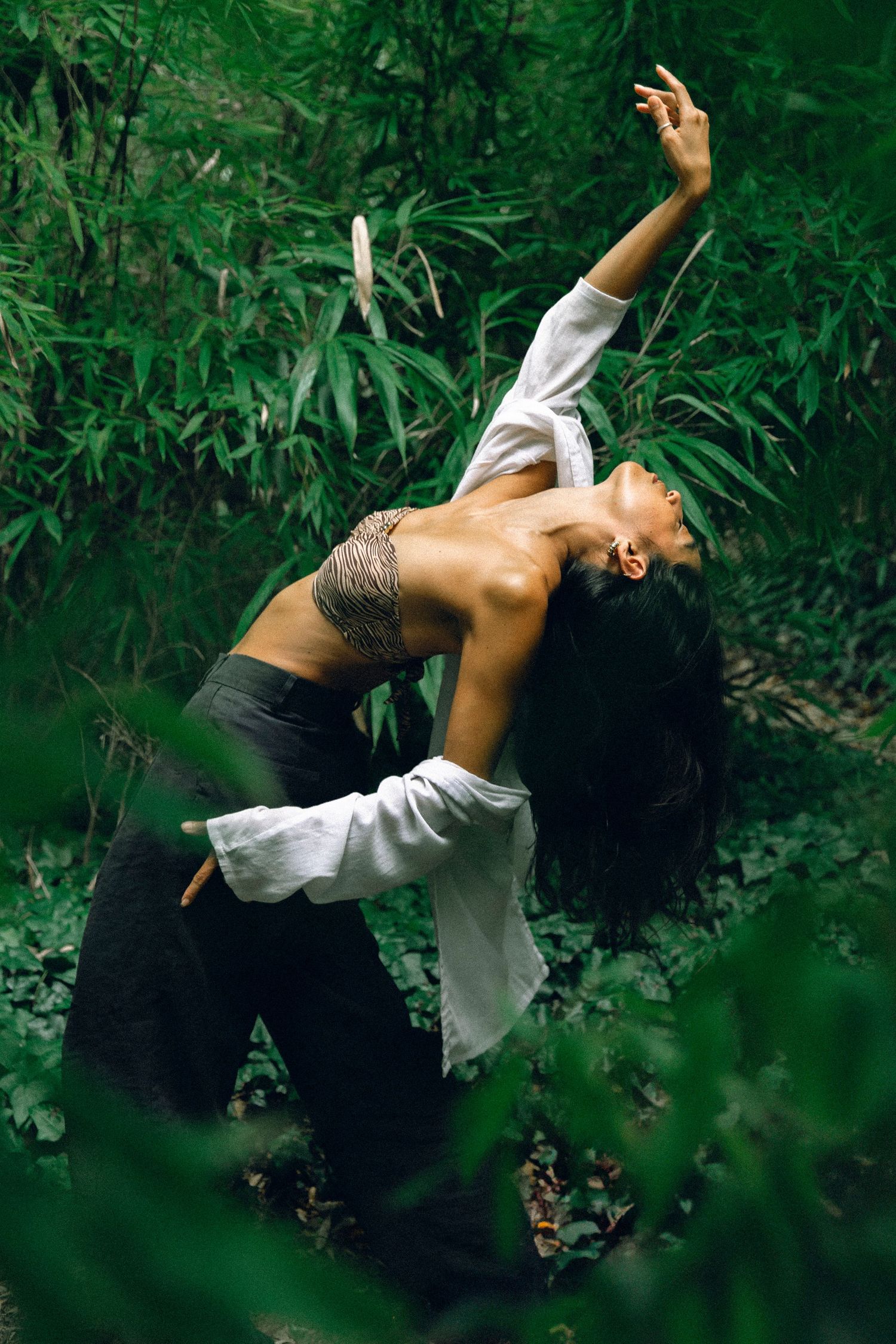 Dynamic dance movement captured in a lush green forest setting.