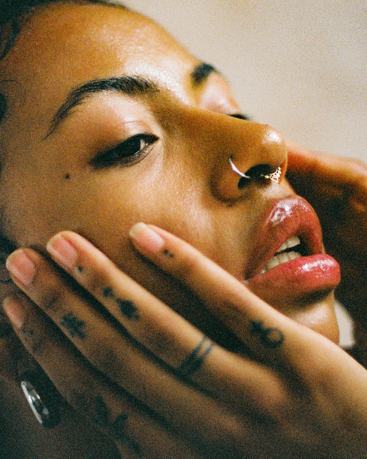 Artistic close-up beauty shot with septum piercing and glossy lips.