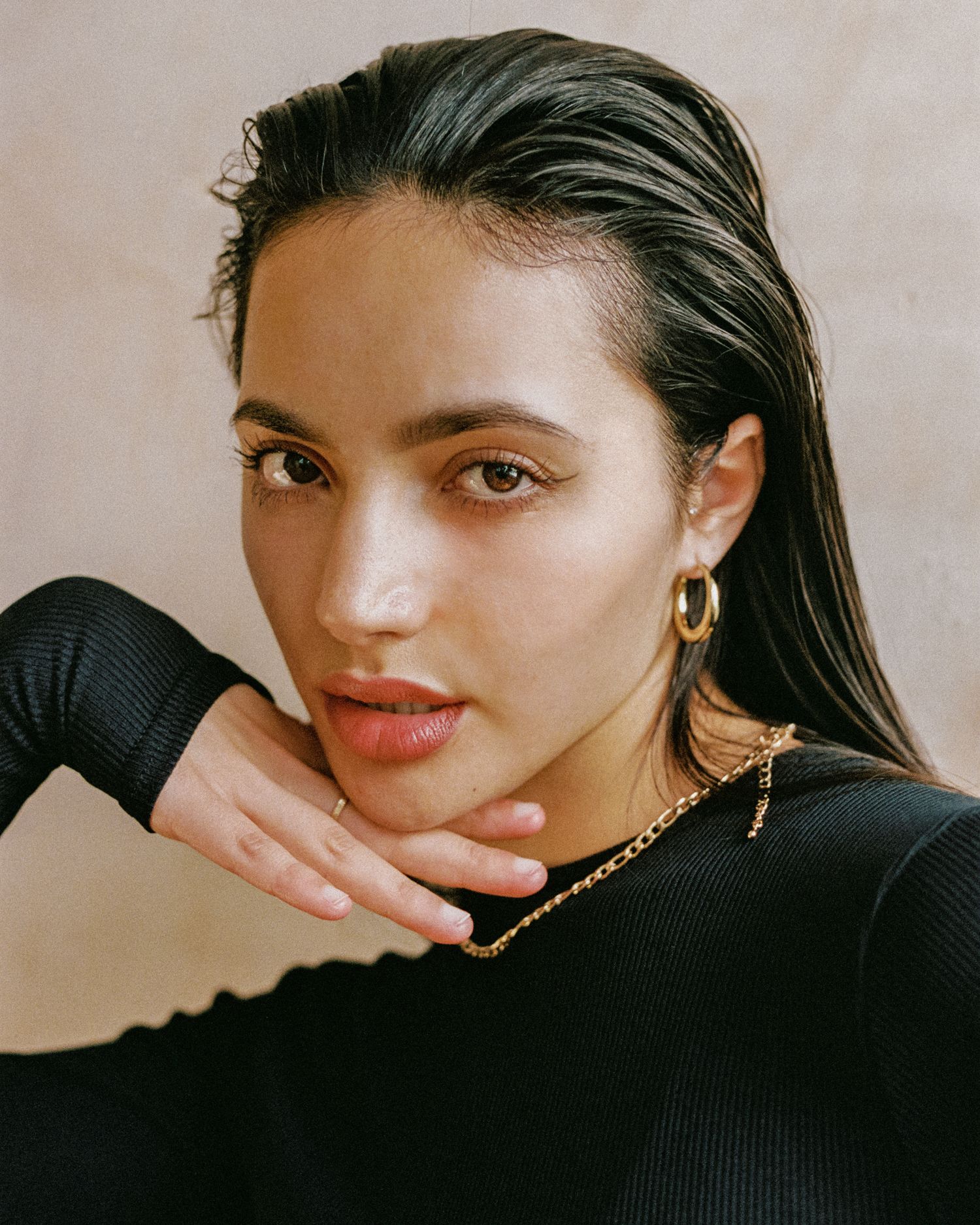 Close-up beauty portrait with gold jewelry and slicked back hair.