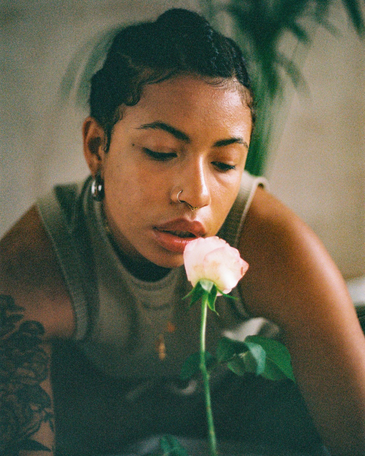 Intimate portrait with pink rose and visible tattoo in warm tones.