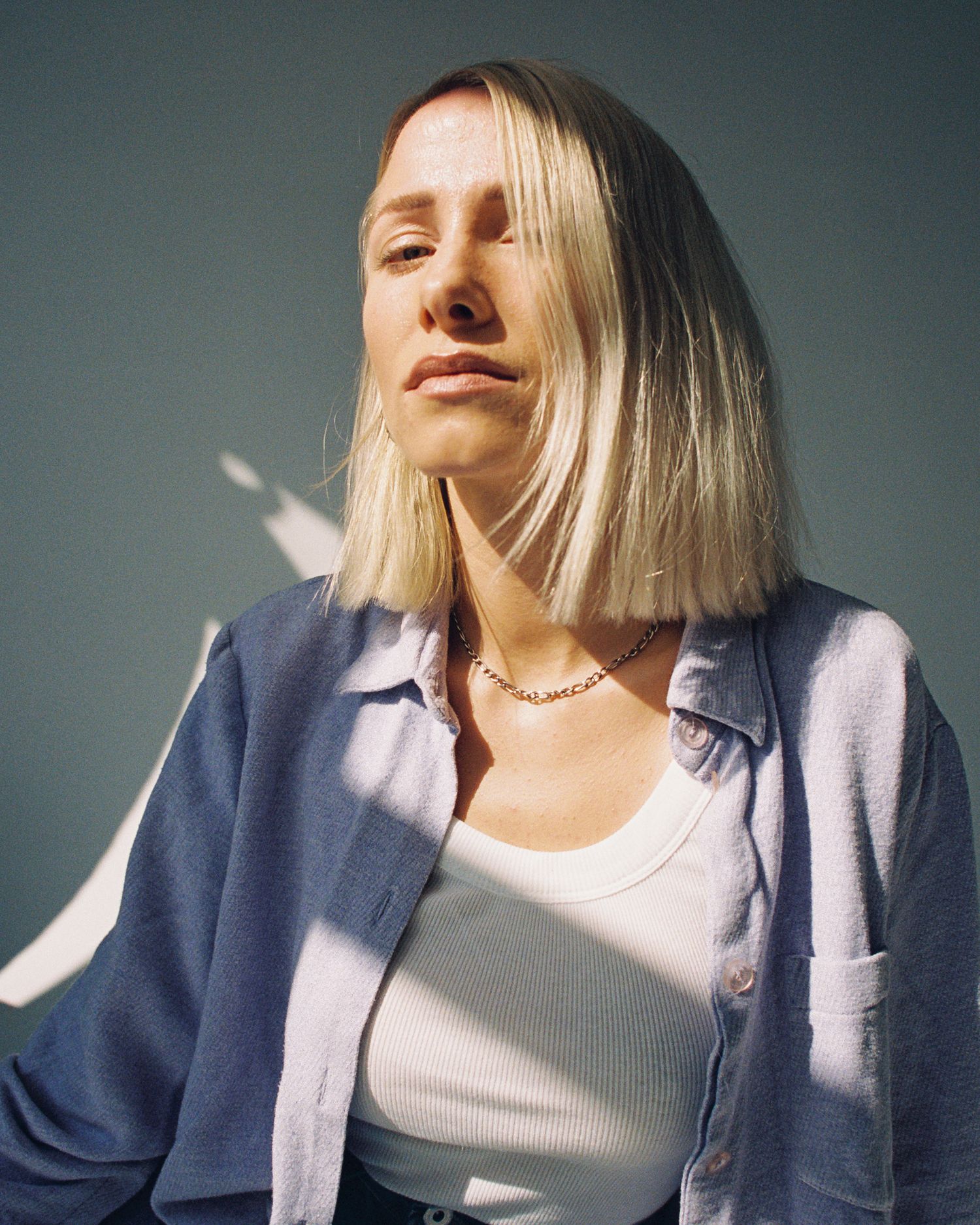 Artistic portrait series showcasing subject wearing blue jacket and white top in dramatic lighting.