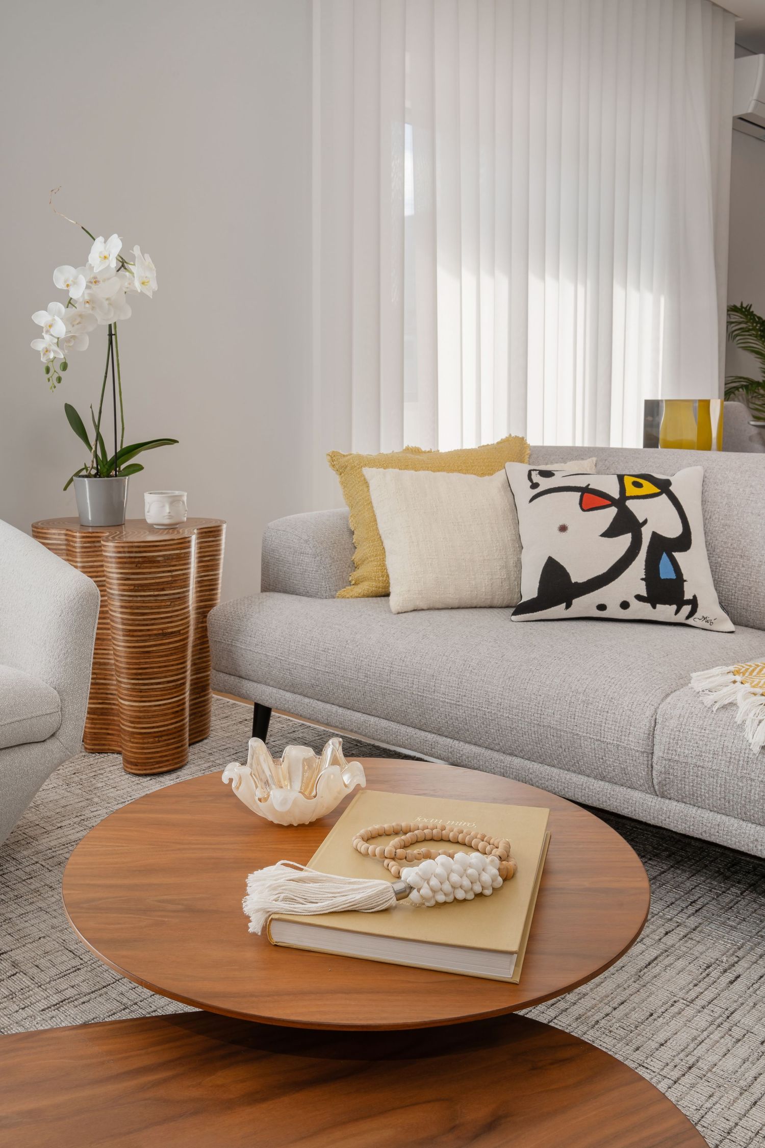 Modern living room with grey sofa, wooden coffee table, and decorative orchid plant.