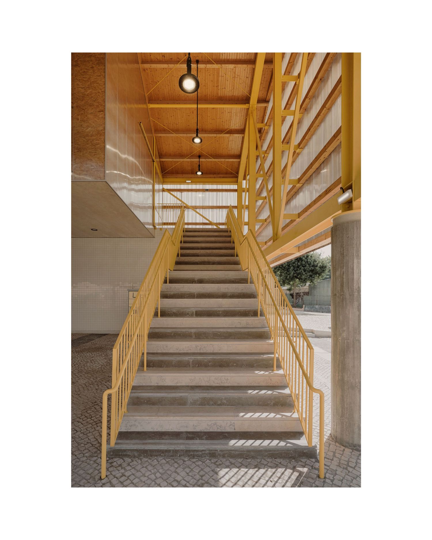 Wooden staircase with metal railings leading upward under warm lighting in a modern building interior.