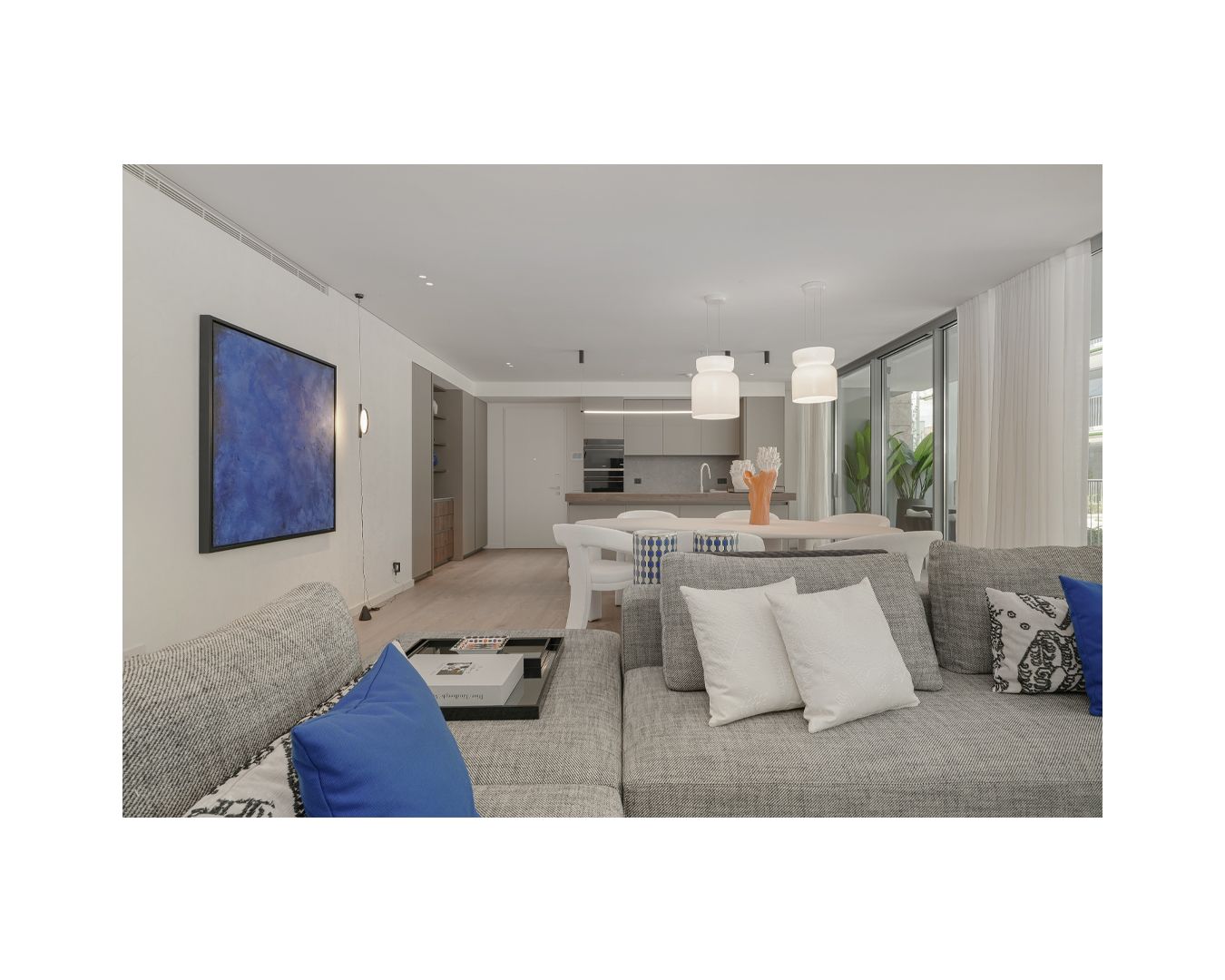 Modern living area with white sectional sofa and bold blue accent wall art.