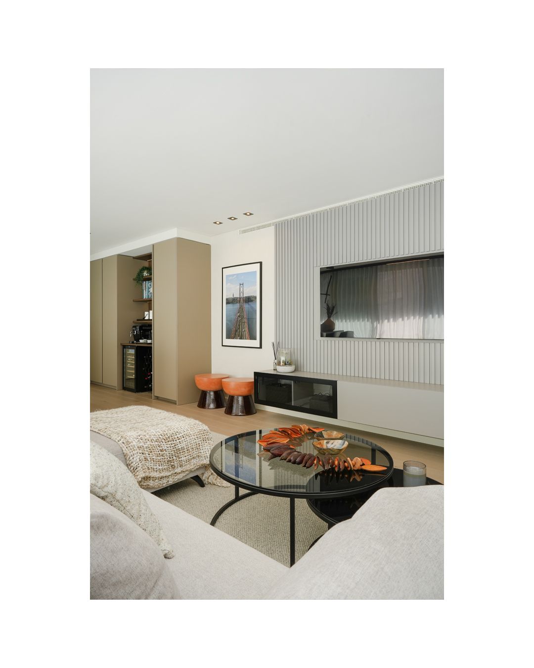 Modern living room with gray walls, white couch, round coffee table and sleek vertical wall paneling.