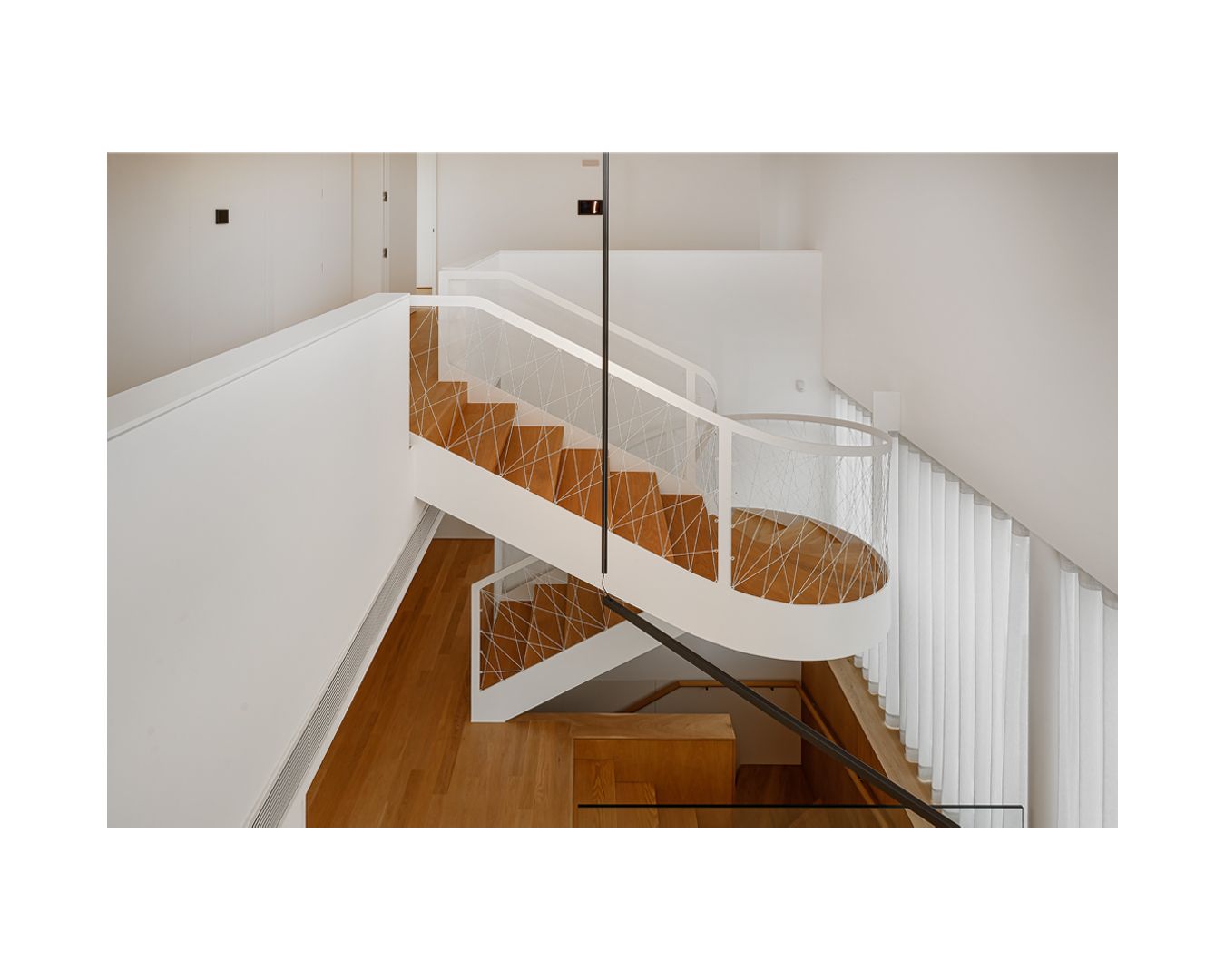Wood and white spiral staircase with elegant curves in a modern interior setting.
