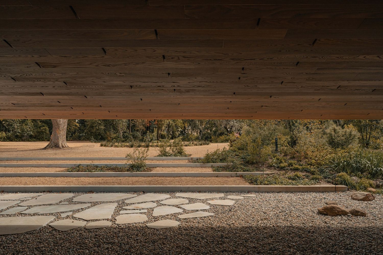 Desert landscape viewed through wooden overhang with stone paved ground in foreground.