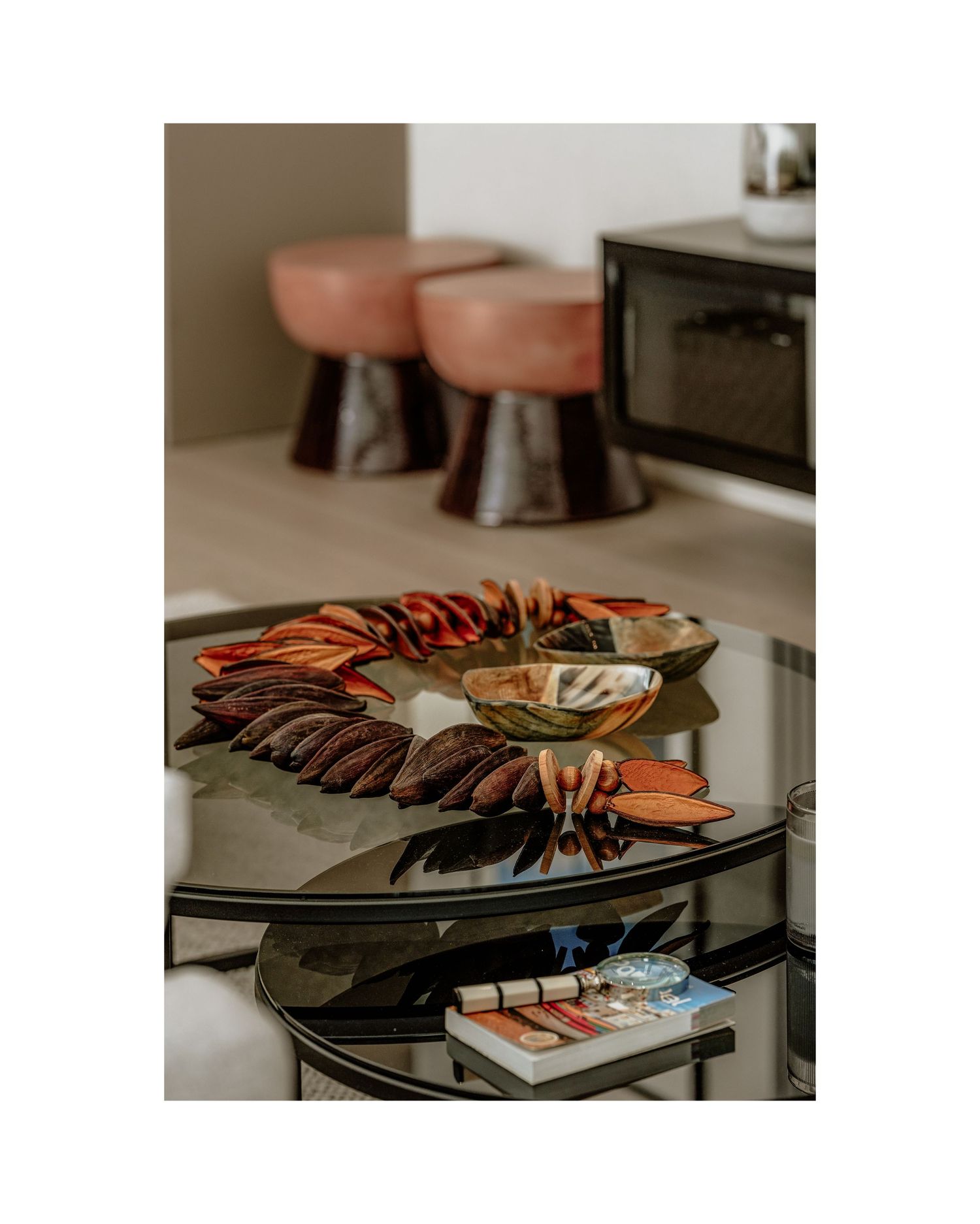 Orange and brown decorative arrangement displayed on dark shelves with coral-colored stools in background.