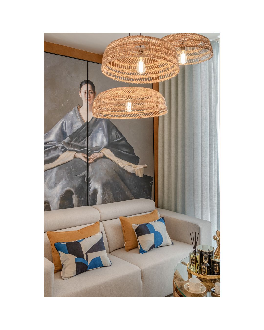 Coastal-inspired living space with woven pendant lights and mountain artwork above beige sofa.