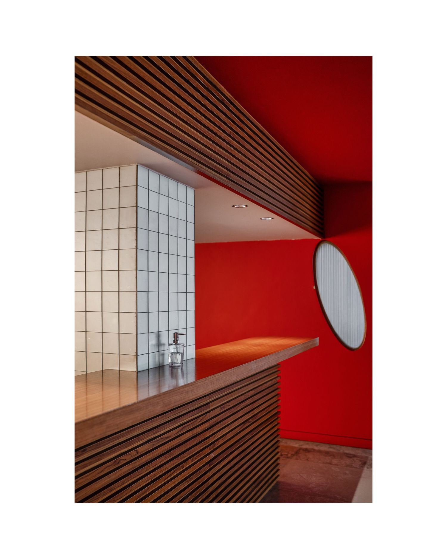 Sleek interior space featuring vibrant red walls, wooden slat ceiling, and white tile details.