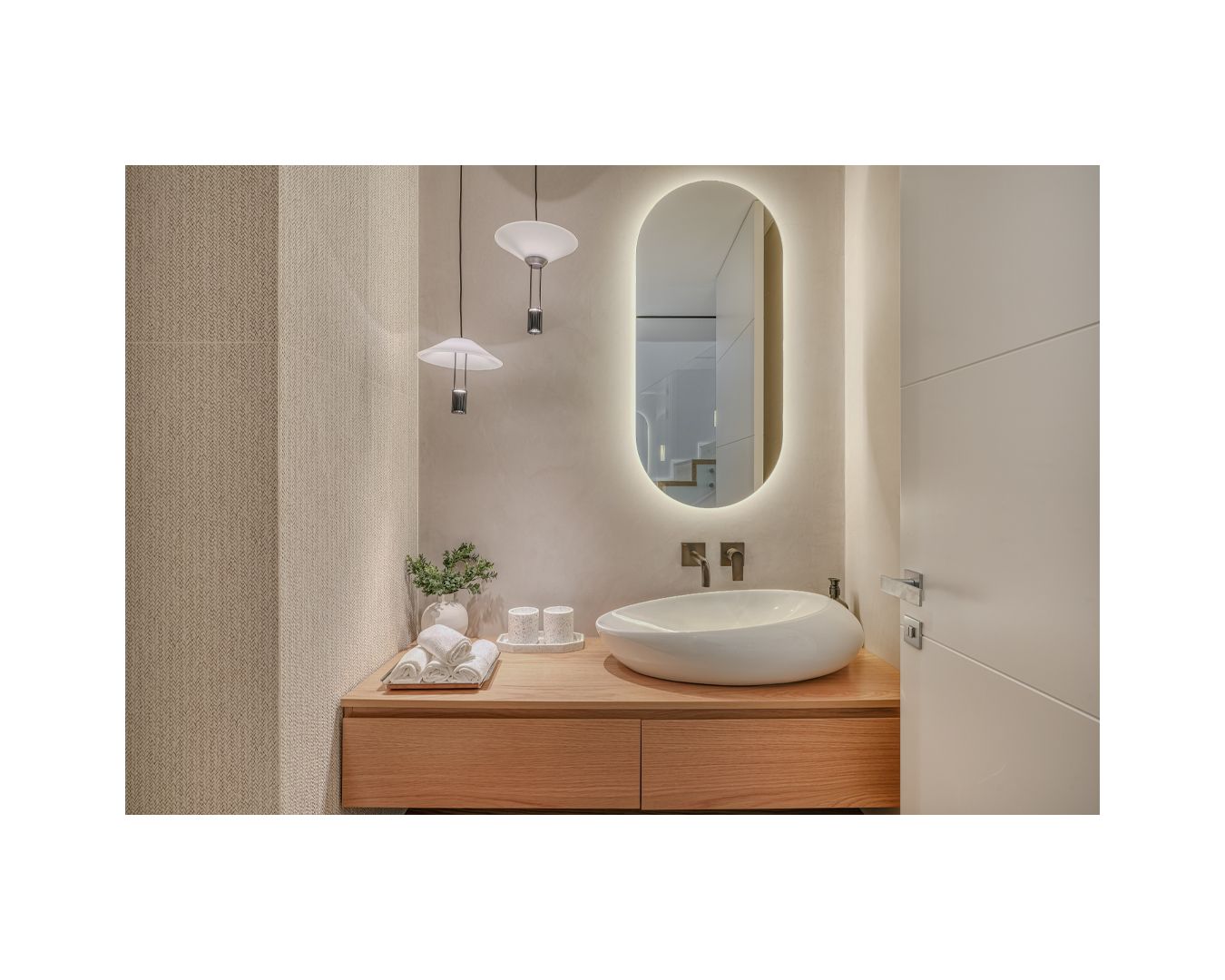 Modern bathroom vanity with backlit oval mirror, vessel sink, and wooden cabinetry.