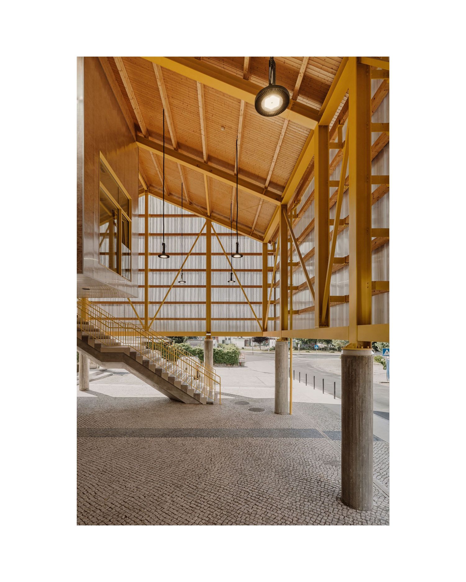 Interior view of a wooden beam structure with exposed rafters and round lighting fixtures.
