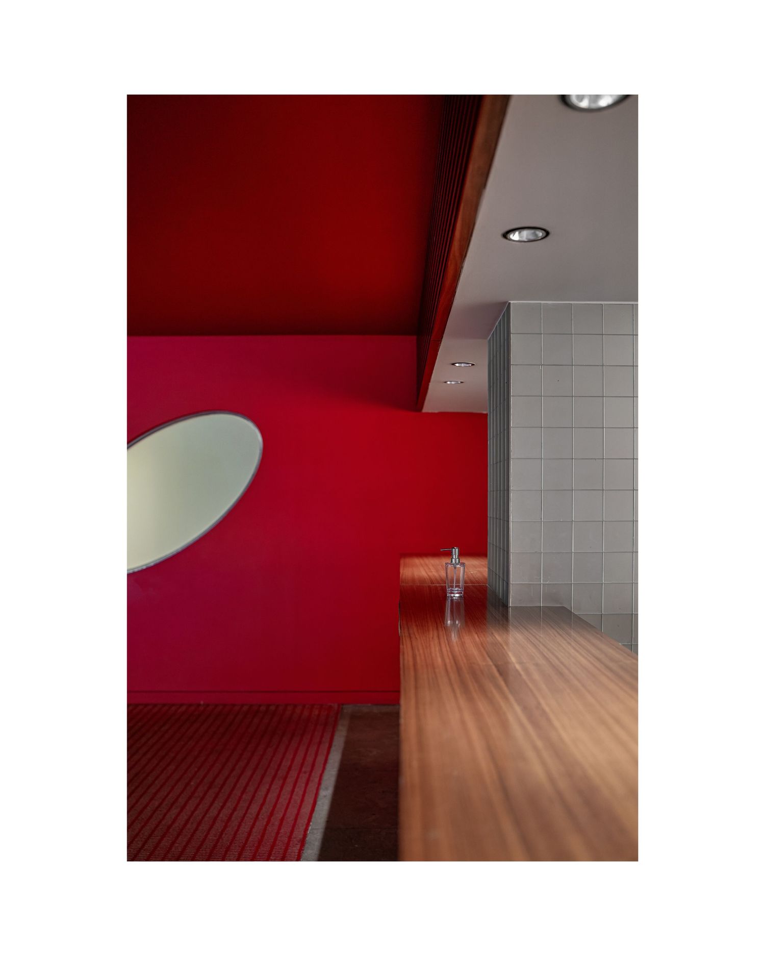 Modern red-walled hallway with wooden flooring and geometric tile accents showcases minimalist interior design.