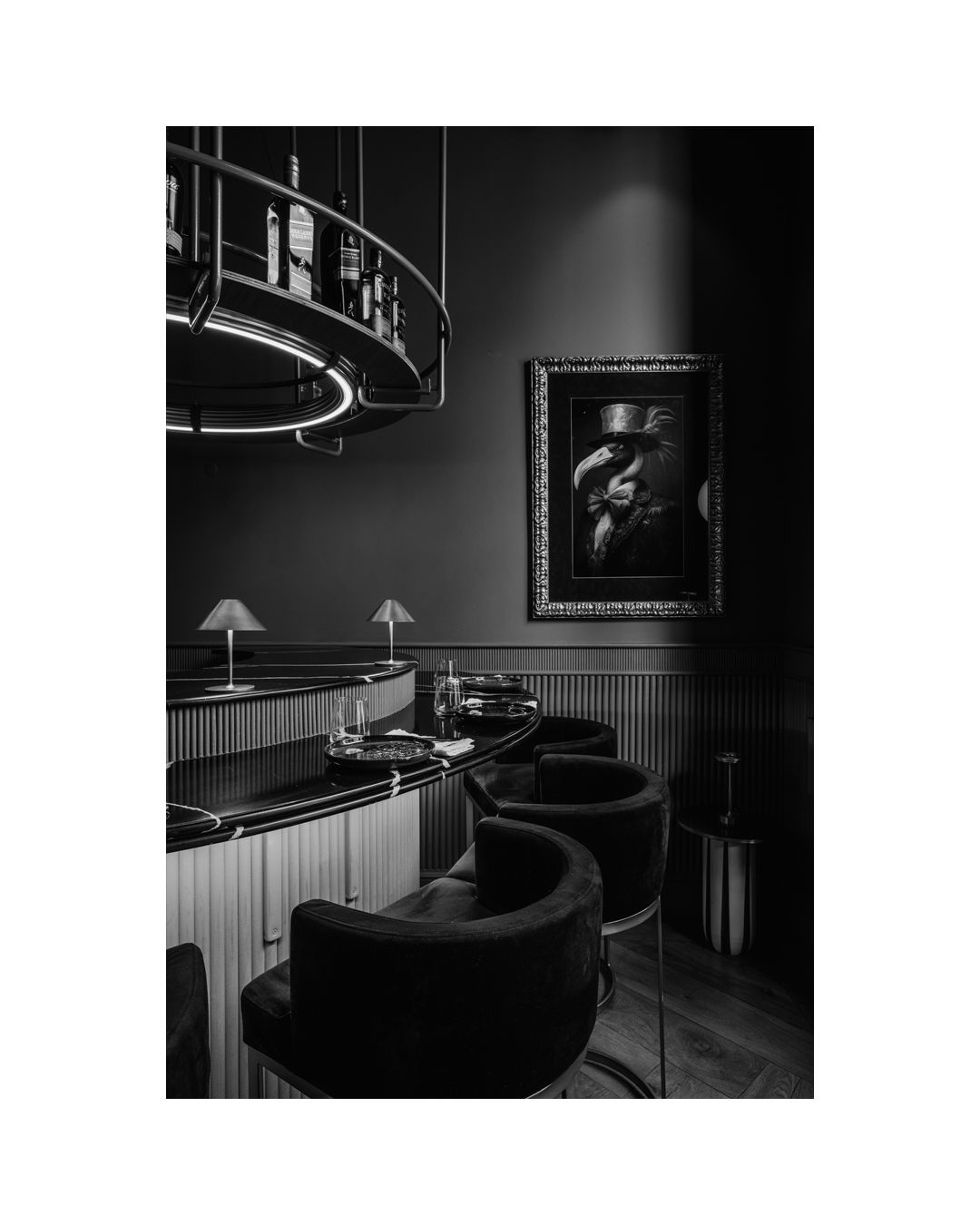 Elegant bar interior with curved seating and dramatic lighting in black and white tones.