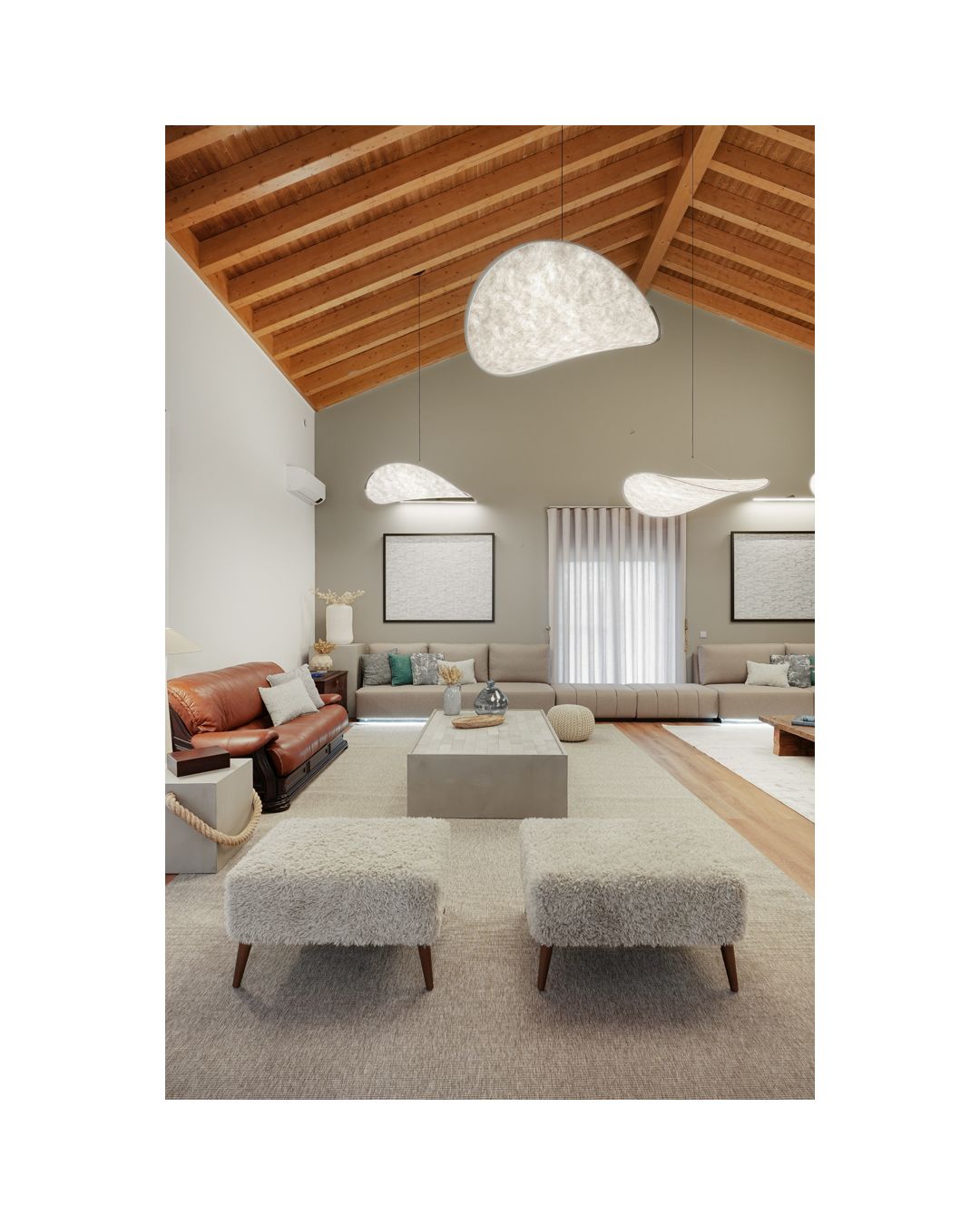 Spacious attic living room with exposed wooden beams and modern cloud-like pendant lights.