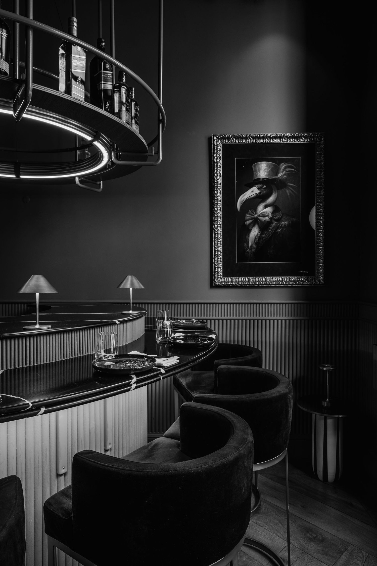 Atmospheric bar area with curved seating and dramatic circular lighting fixture in noir style.