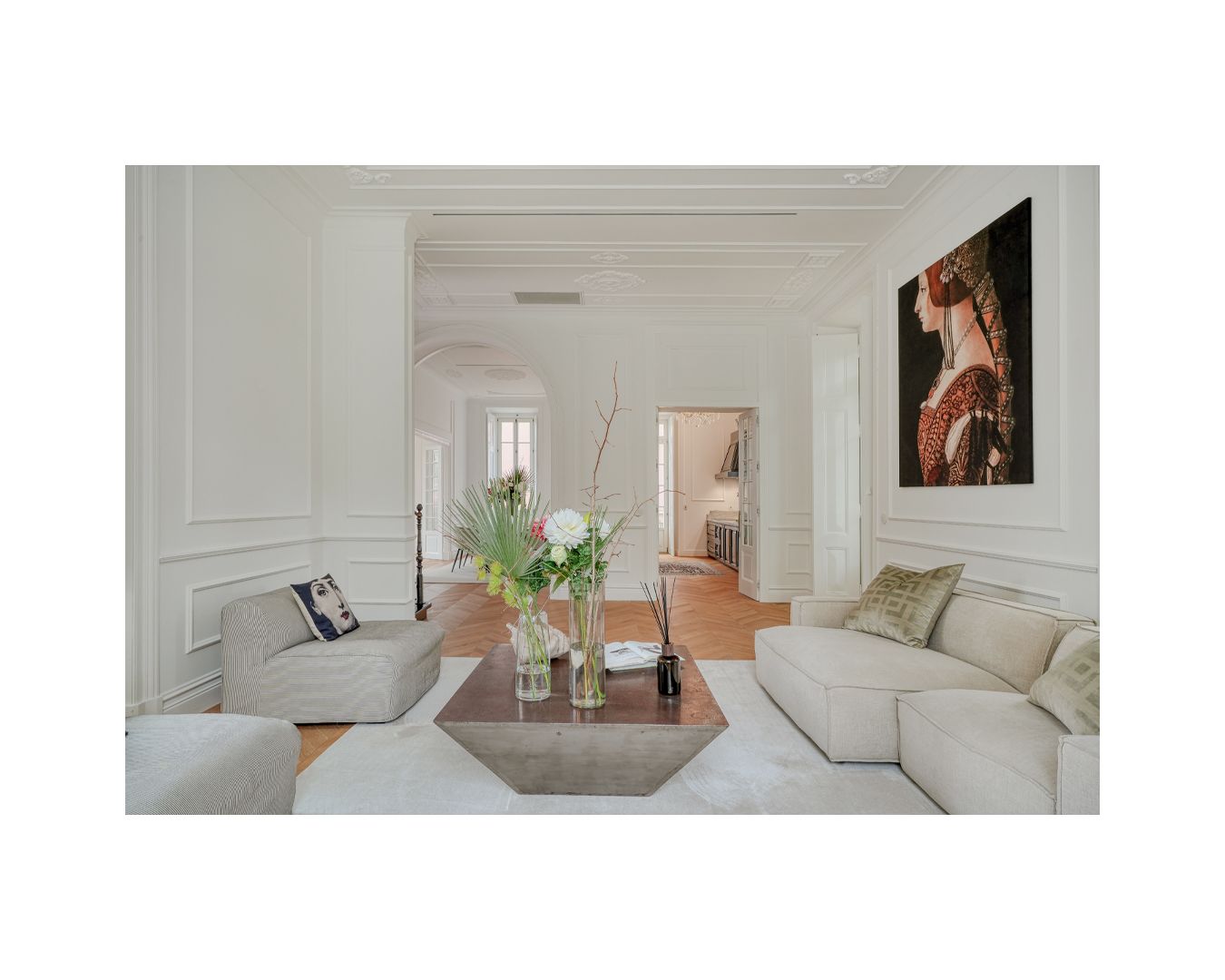 Elegant white living room with classic moldings, modern artwork, and contemporary furniture.