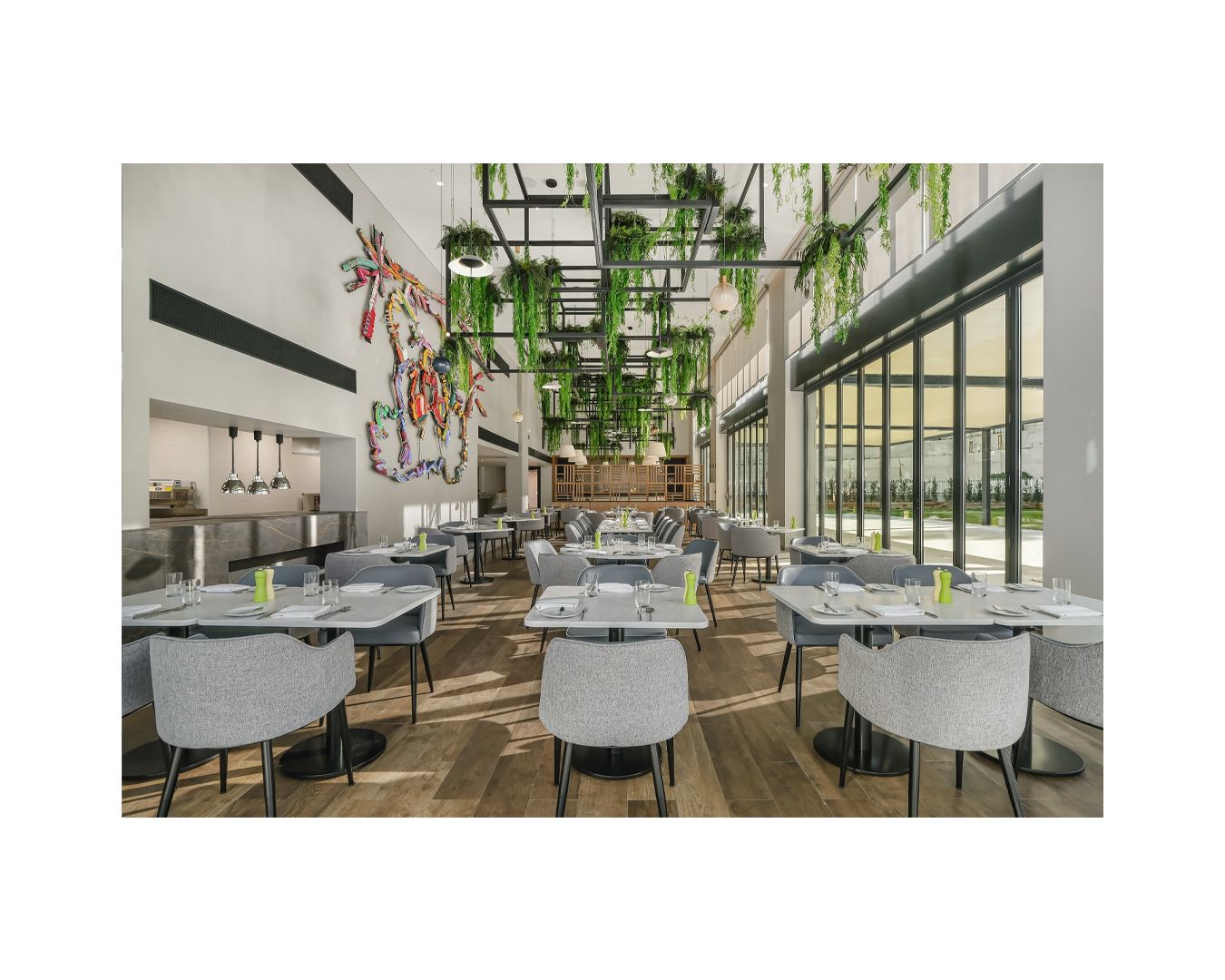 Elegant restaurant interior with white chairs, hanging plants, and abundant natural lighting.