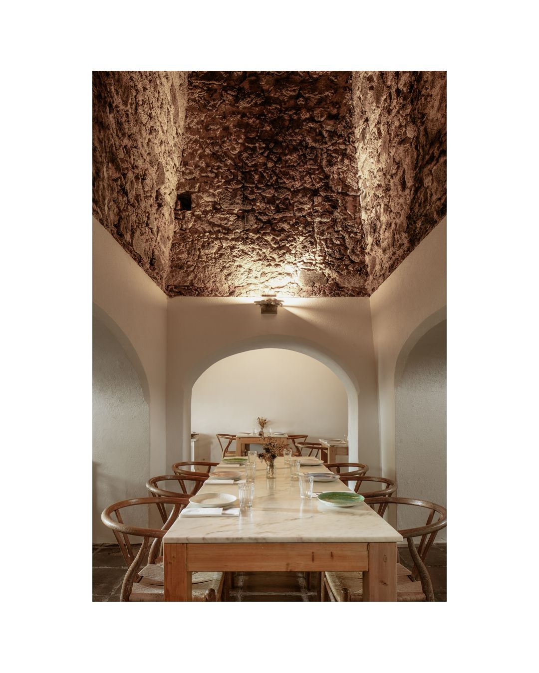 Sophisticated dining room with exposed brick vaulted ceiling and white modern table settings.