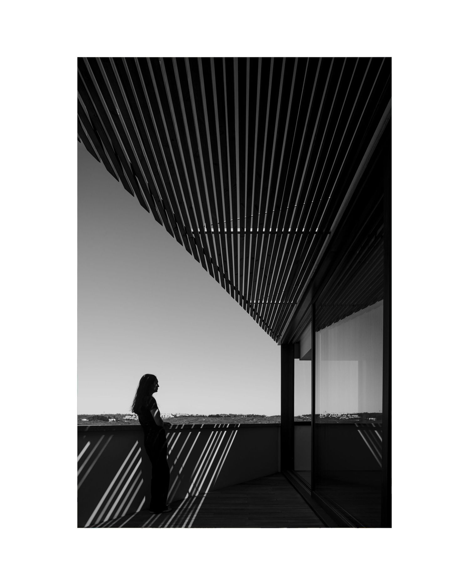 Black and white architectural photograph showing geometric lines and silhouette against sky.